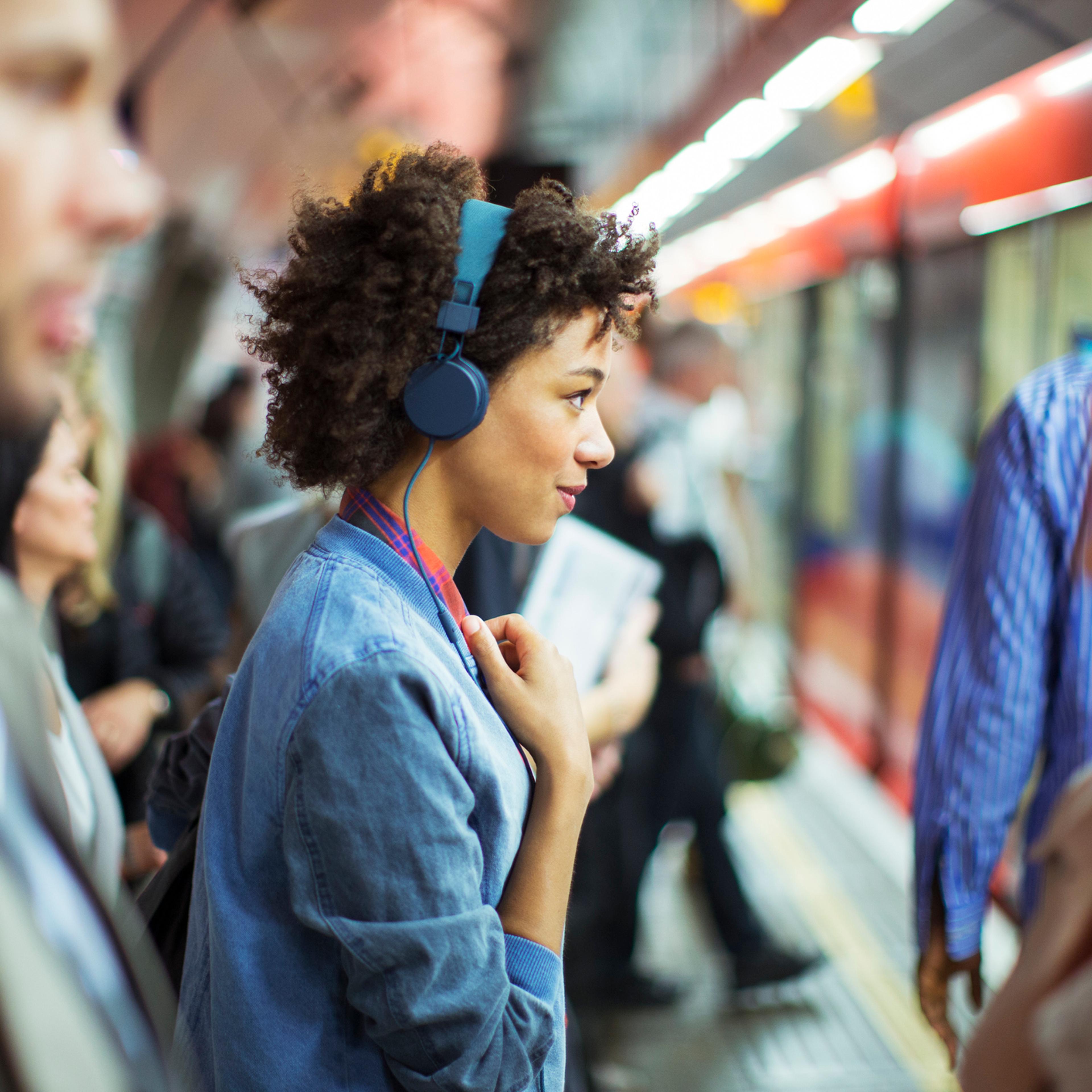 Woman listening to headphones in train station