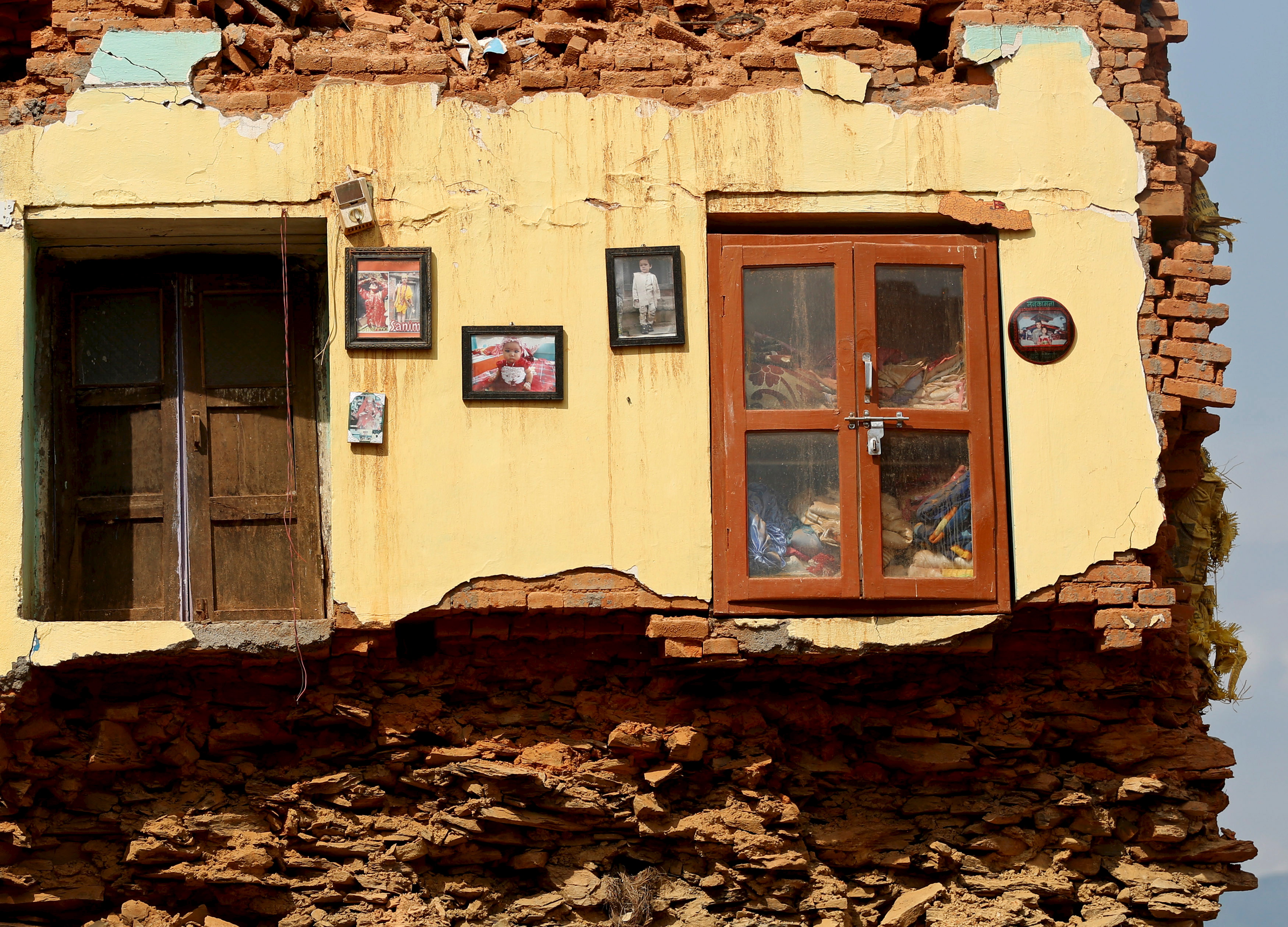 Framed pictures are seen hanging from the wall of a house damaged by earthquakes in Sindhupalchowk district, Nepal