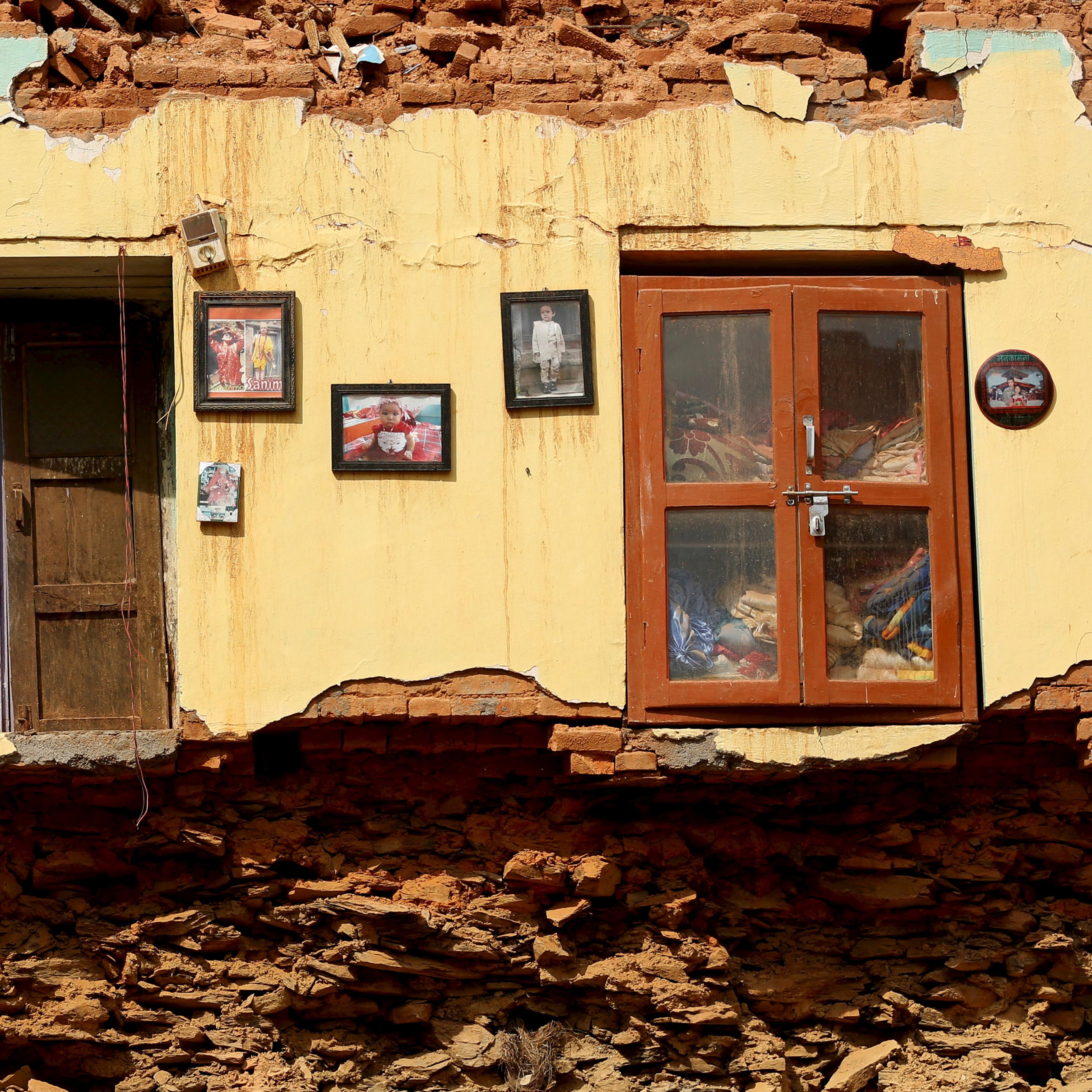 Framed pictures are seen hanging from the wall of a house damaged by earthquakes in Sindhupalchowk district, Nepal
