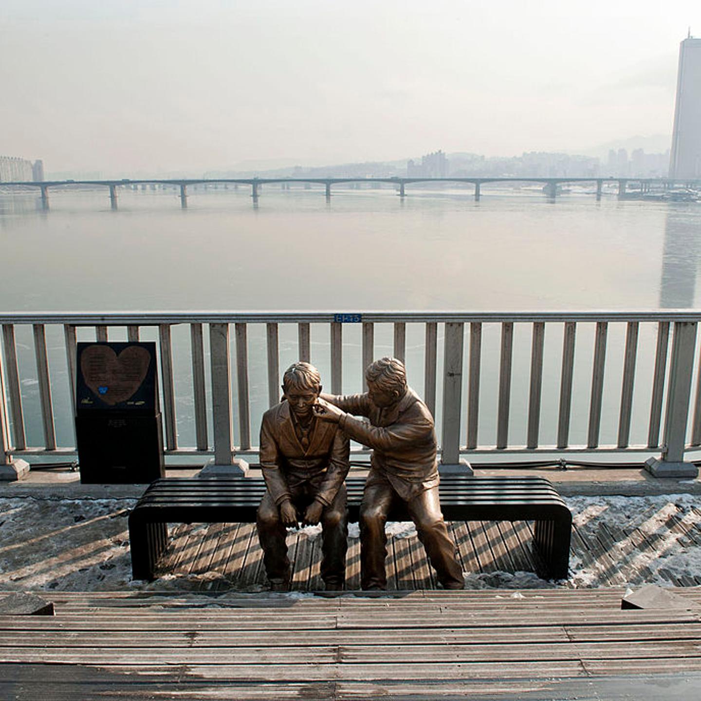 This photo taken on January 11, 2013 shows a statue of a man comforting a person placed by the government to dissuade potential suicides at Mapo Bridge—a common site for suicides—over Seoul's Han river.