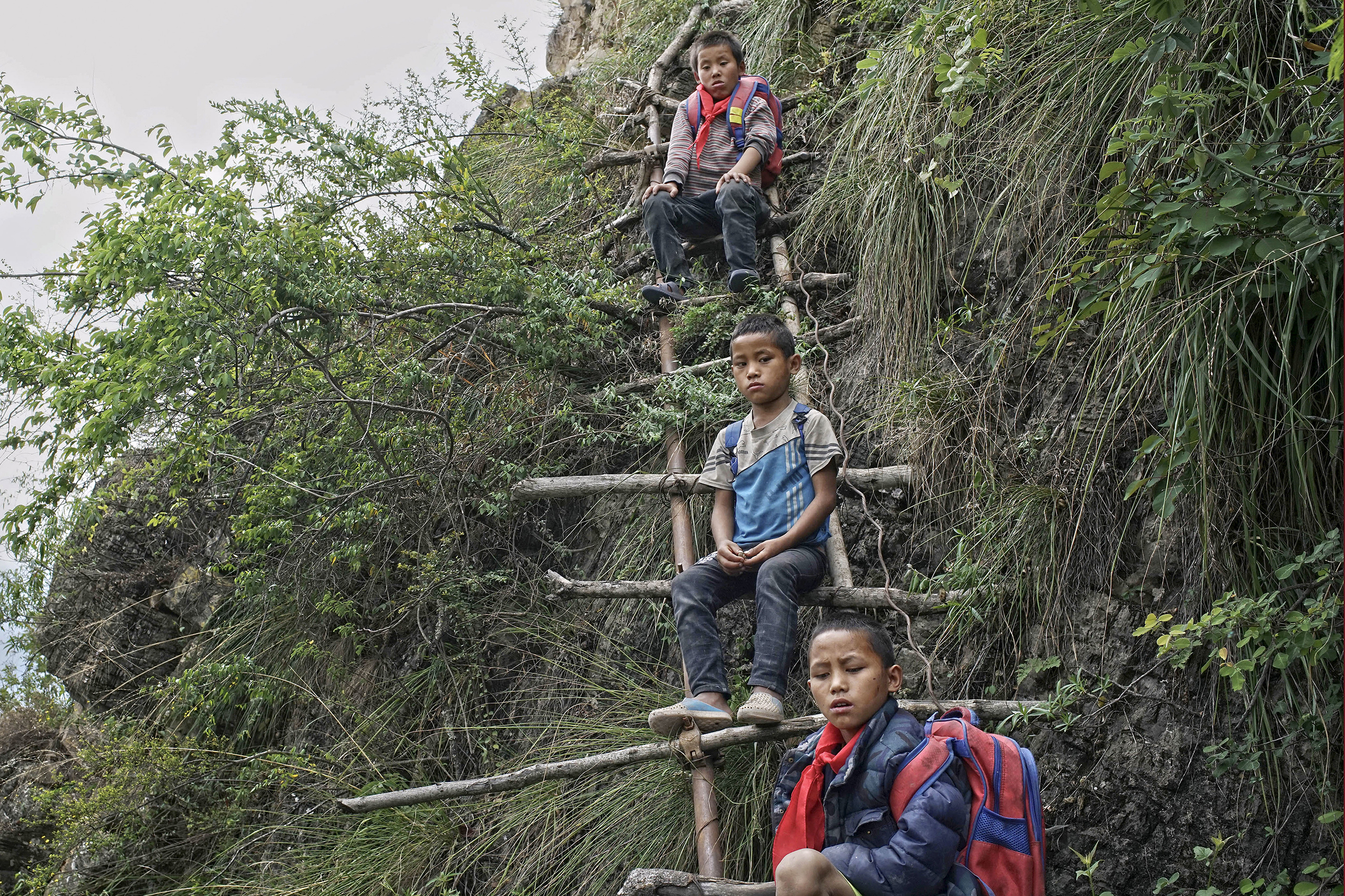Children carrying their schoolbags take rest on the ladder built on a cliff in Zhaojue county, southwest China's Sichuan province on May 14, 2016.