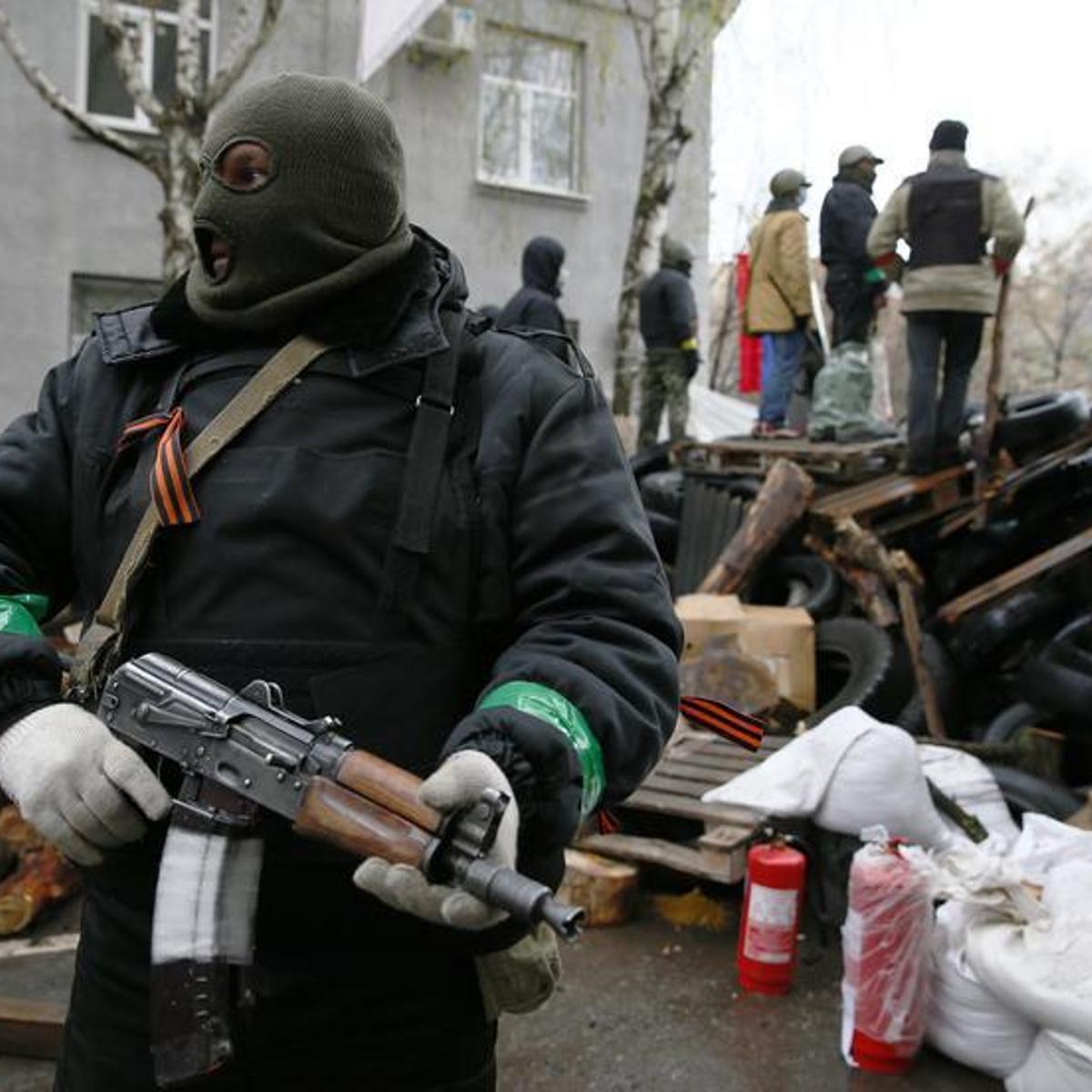 An armed man stands next to a barricade in front of the police headquarters in Slaviansk