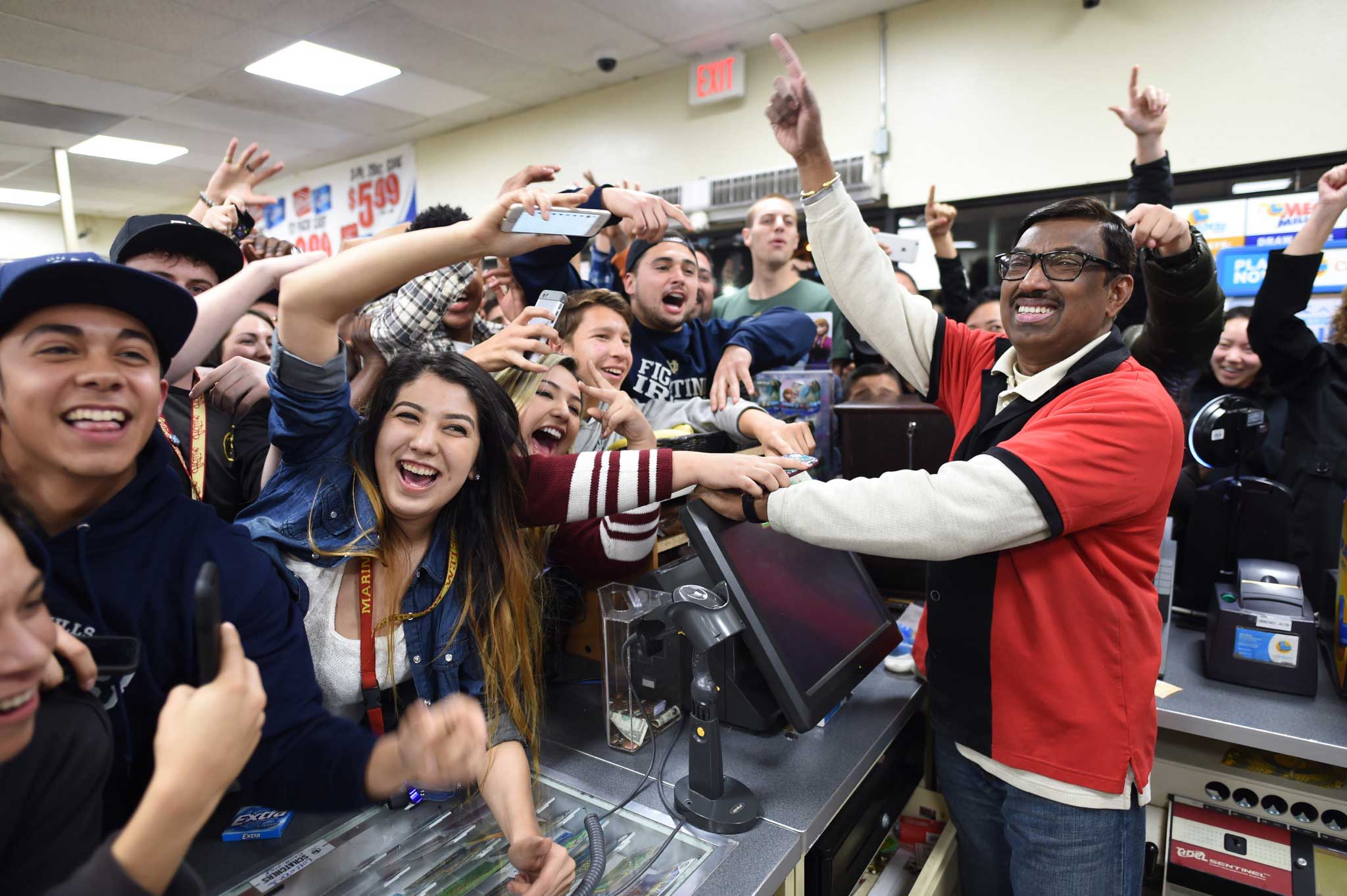 7-Eleven store clerk M. Faroqui celebrates with customers after learning the store sold a winning Powerball ticket, Chino Hills, Calif., Jan. 13, 2016.