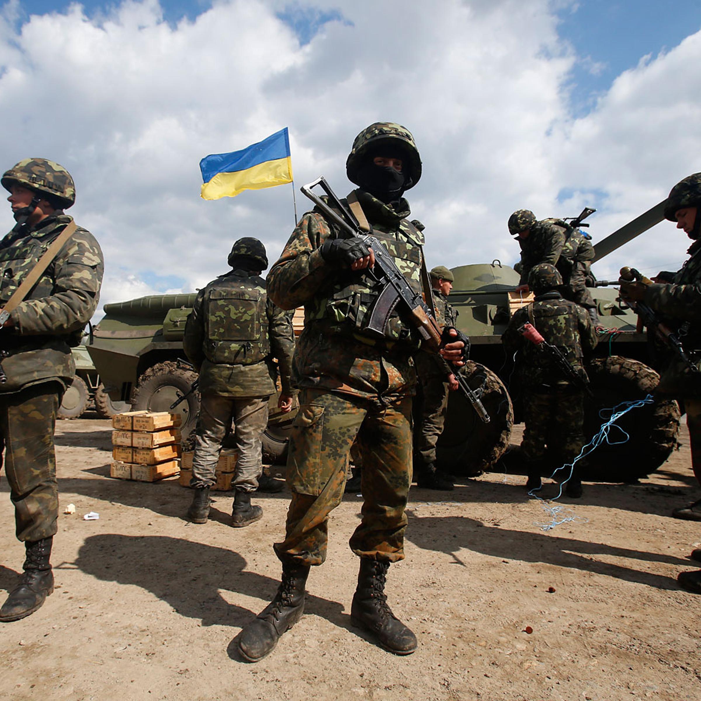 Ukrainian army troops receive ammunition, with a Ukrainian flag in the back, in a field on the outskirts of Izyum, Eastern Ukraine, April 15, 2014.