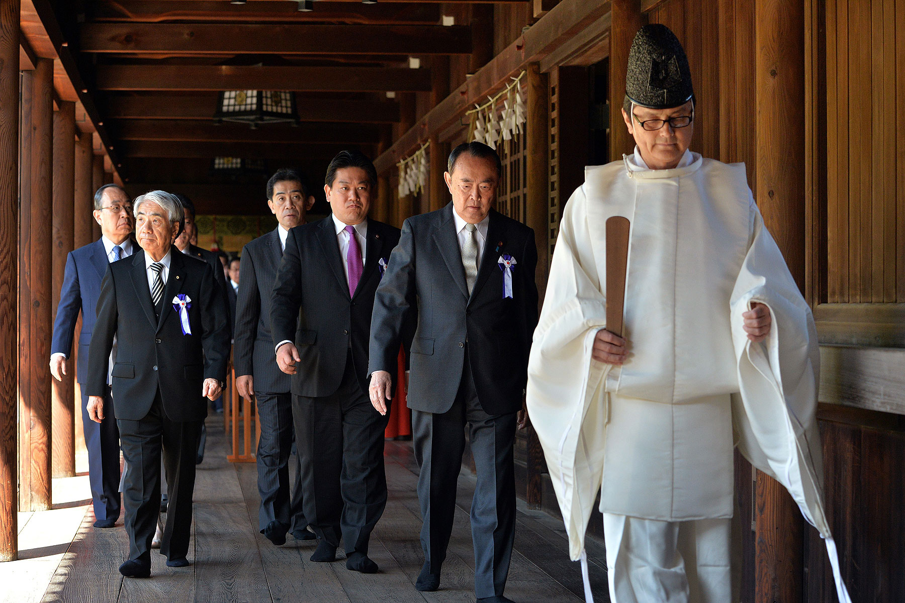 Japanese lawmakers follow a Shinto priest during a visit to the controversial Yasukuni Shrine to honor war dead during a spring festival in Tokyo on April 22, 2014