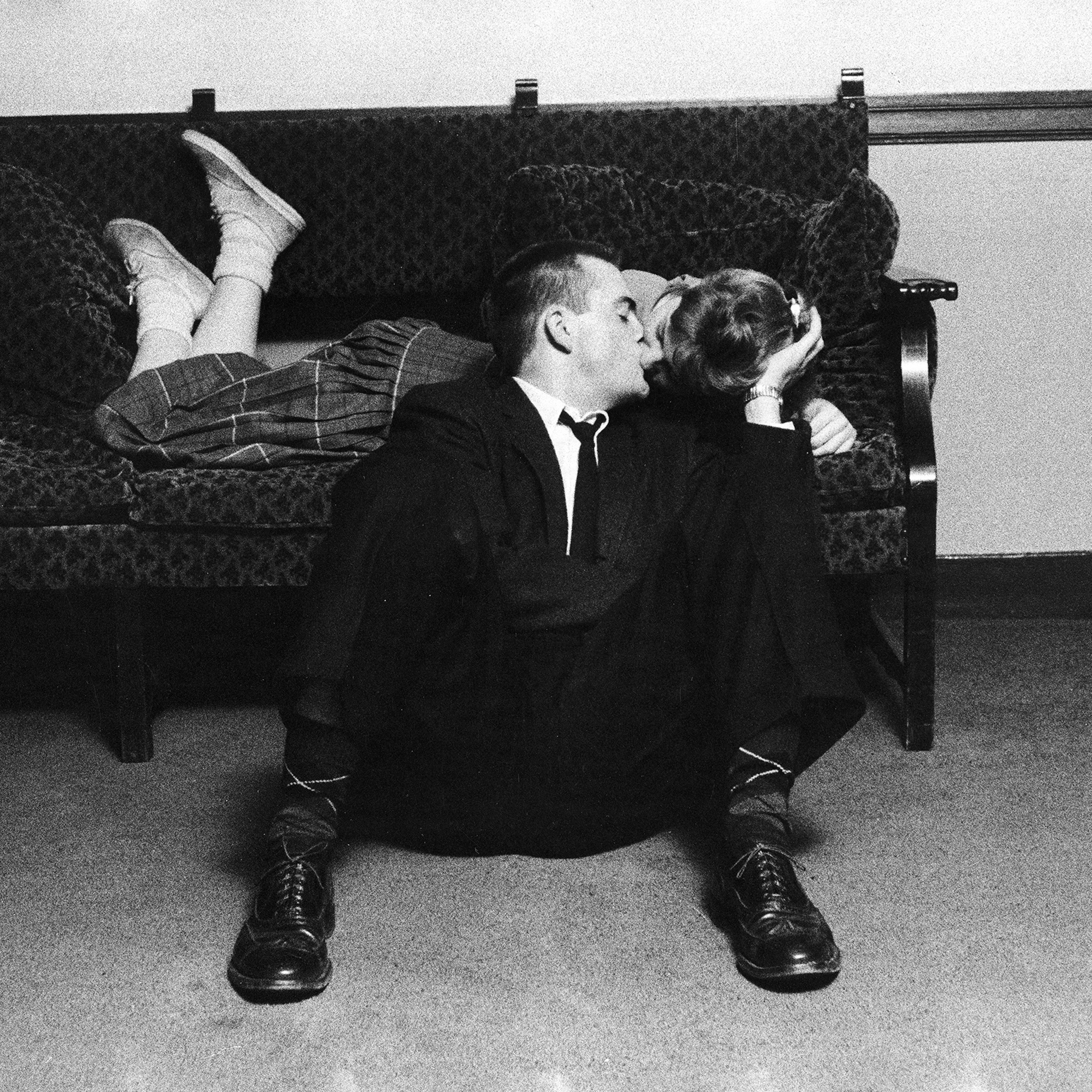 University of Michigan student couple engaged in an impromptu kiss, which was forbidden conduct even before school ban, because earlier rules required couples to have both feet on the floor, in the Union Building on campus. 1957.