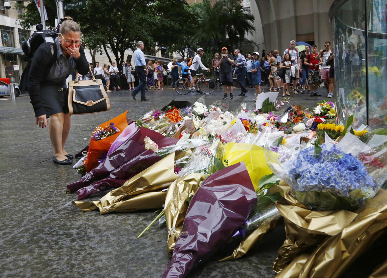 A woman reacts after placing a floral tribute for those who died in the Sydney cafe siege, near the site of the incident, in Martin Place