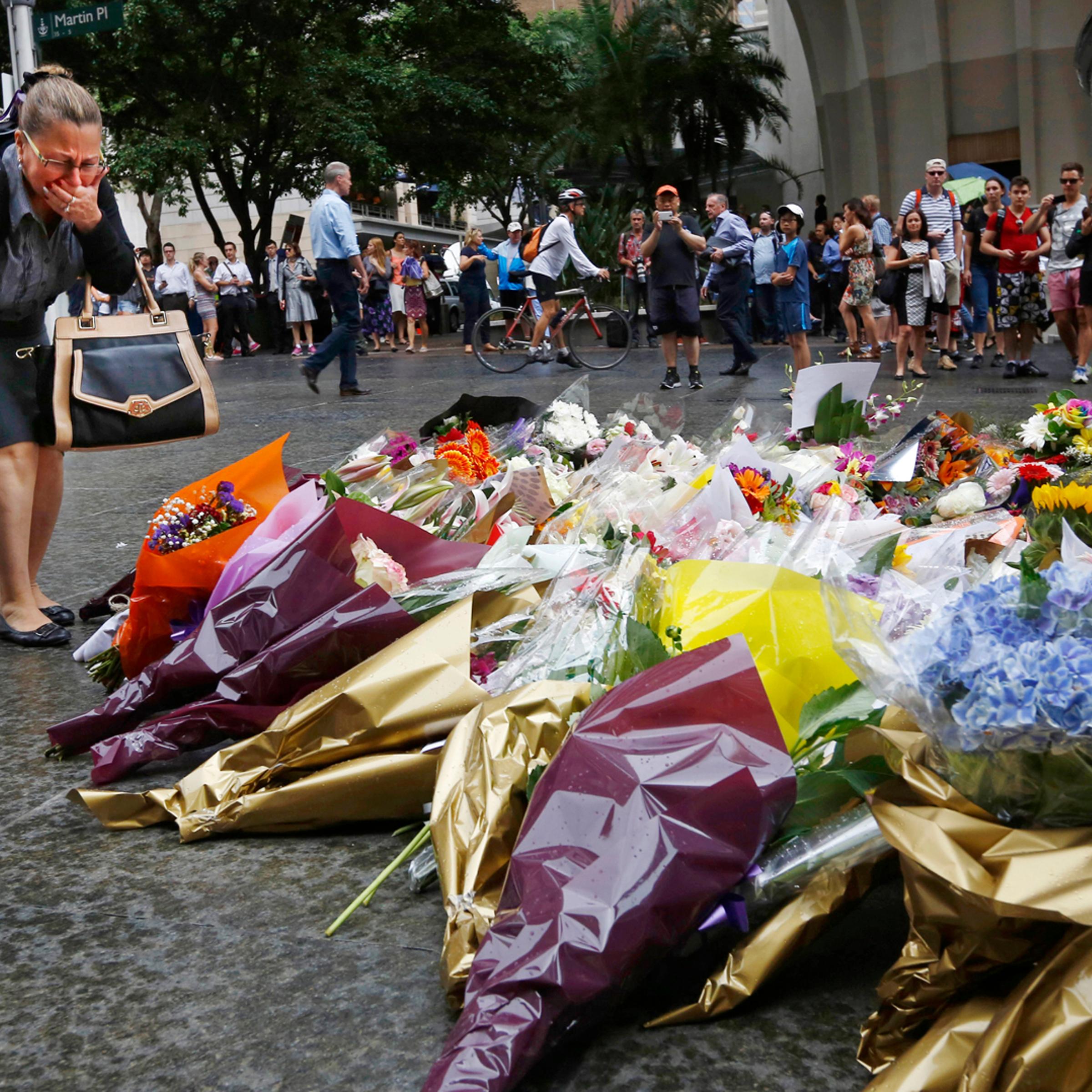 A woman reacts after placing a floral tribute for those who died in the Sydney cafe siege, near the site of the incident, in Martin Place