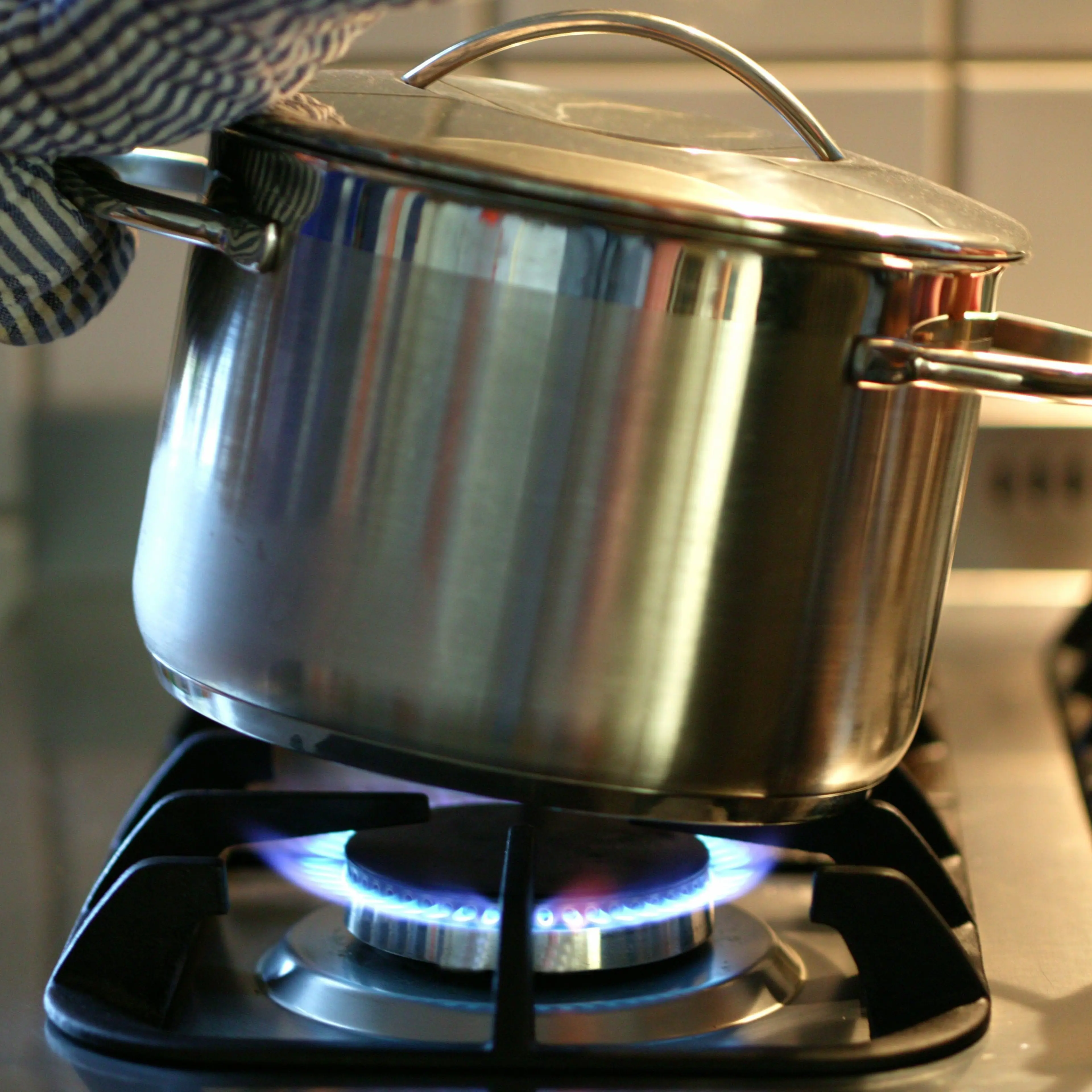 A pot is beeing taken from the gas cooker.
