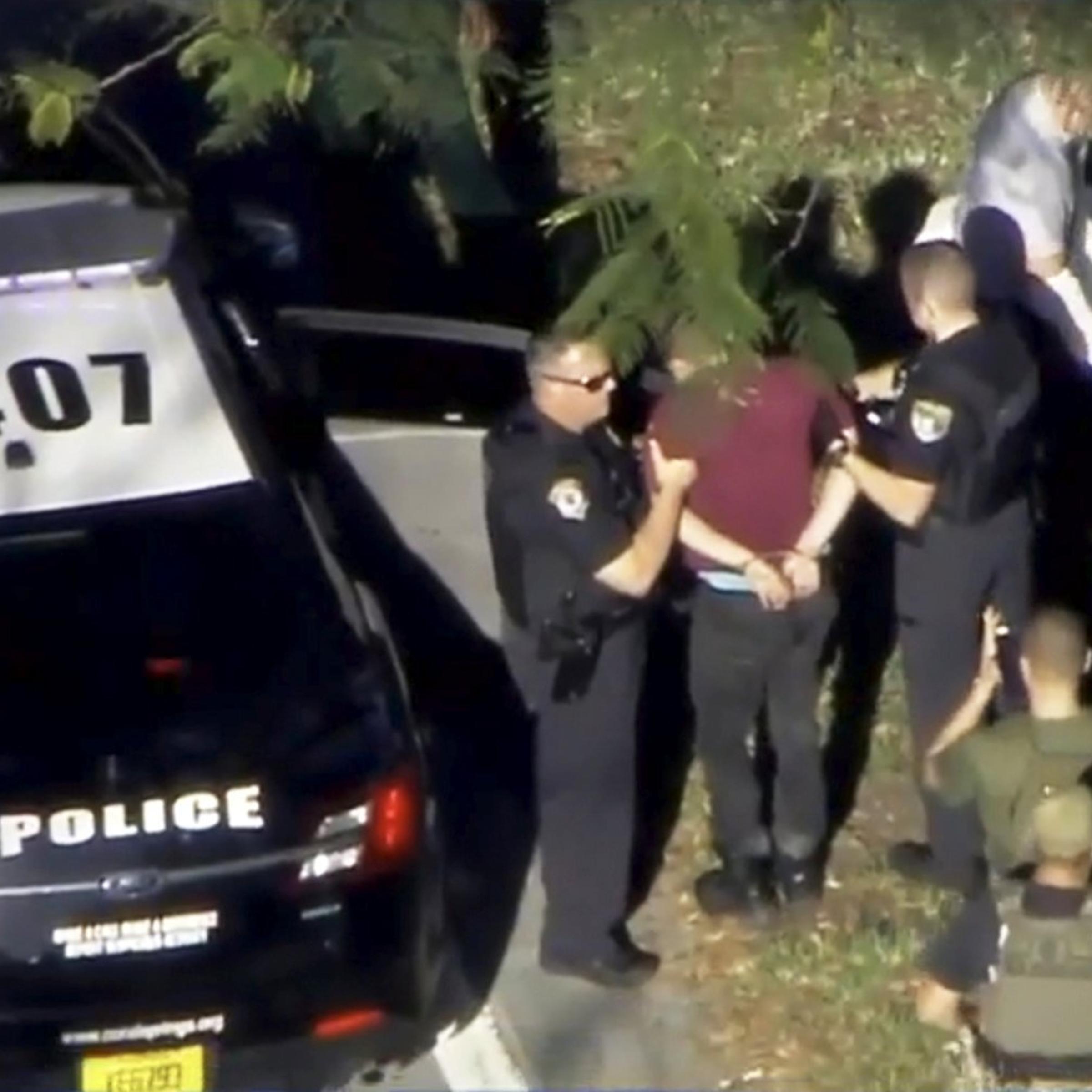 A man placed in handcuffs is led by police near Marjory Stoneman Douglas High School following a shooting incident in Parkland