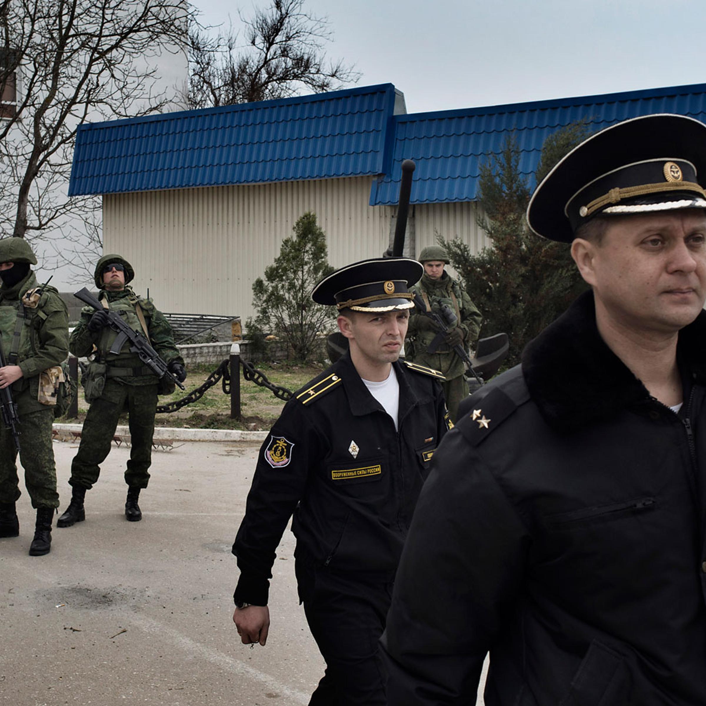 Ukrainian naval officers passed by Russian military personnel as they left the Ukrainian naval headquarters in Sevastopol on Wednesday after Russian forces and local militiamen seized control of the facility, March 19, 2014.