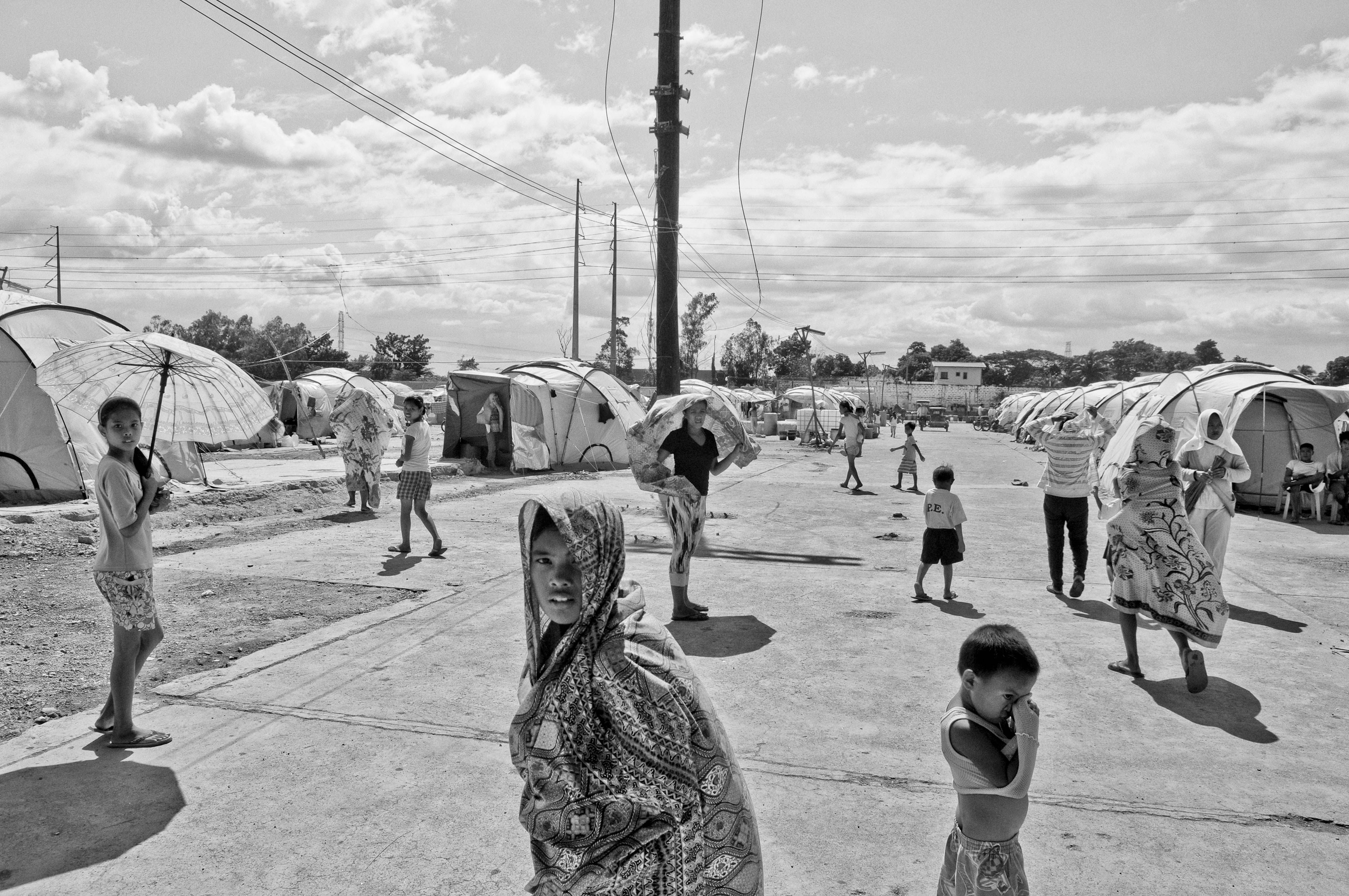 Families that have been displaced for several months due to stagnant floodwaters seek temporary shelter in a rundown factory on Oct. 23, 2012 in Laguna, Philippines.