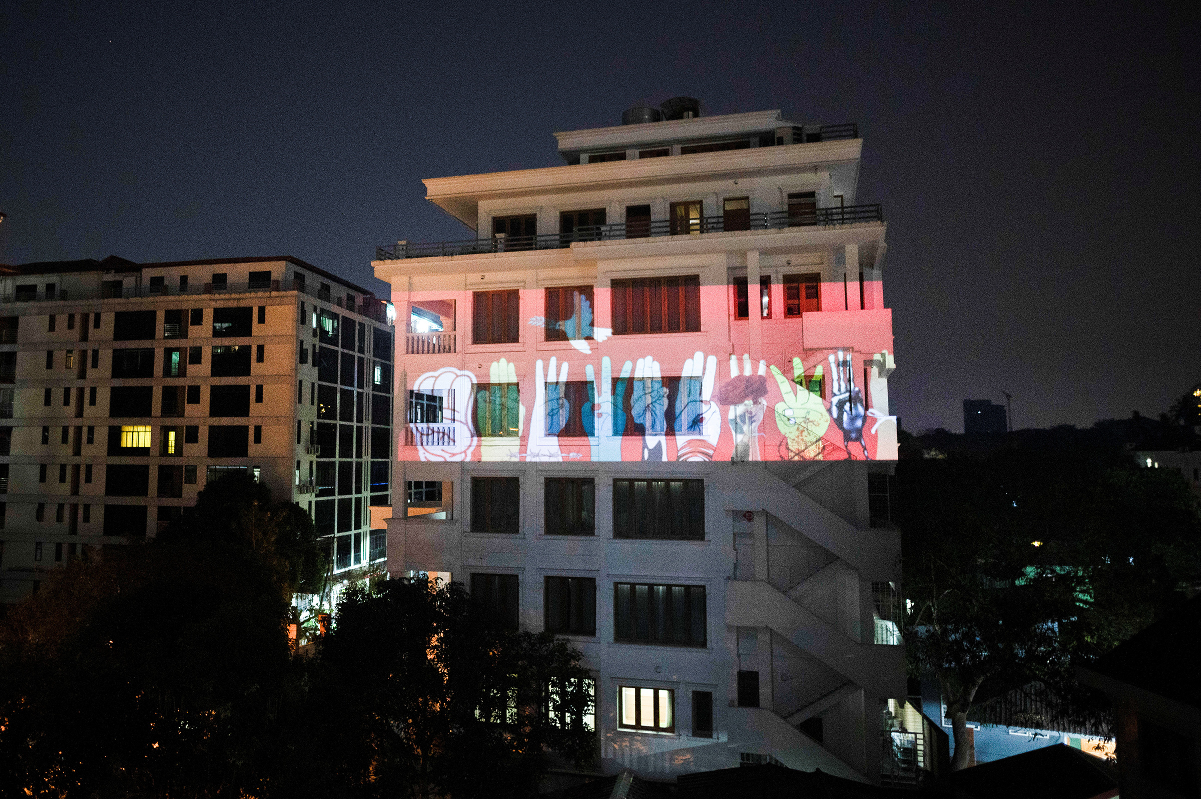 An image of three-finger salute is projected on a building during a night protest against the military coup and to demand the release of elected leader Aung San Suu Kyi, in Yangon, Myanmar, Feb. 9