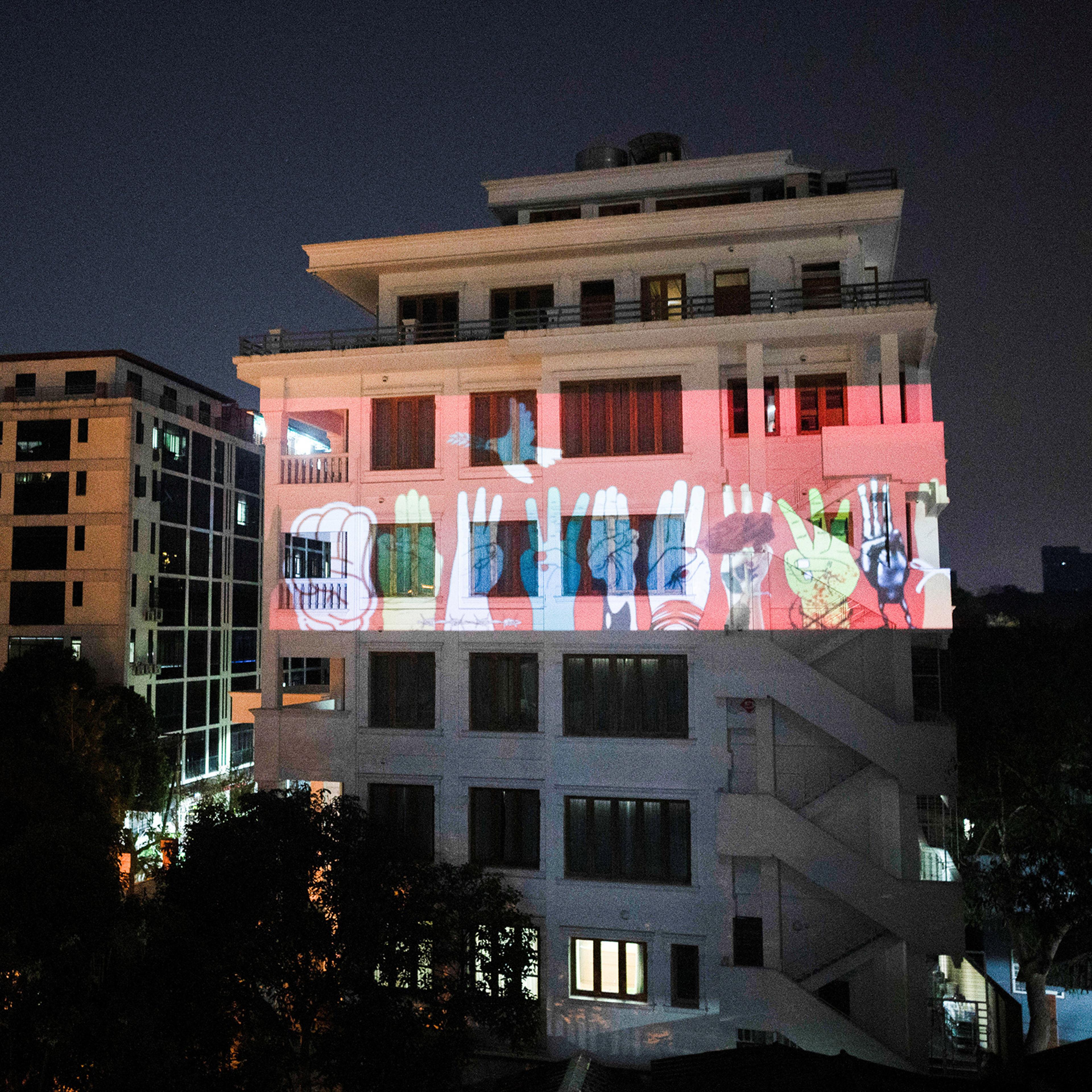 An image of three-finger salute is projected on a building during a night protest against the military coup and to demand the release of elected leader Aung San Suu Kyi, in Yangon, Myanmar, Feb. 9