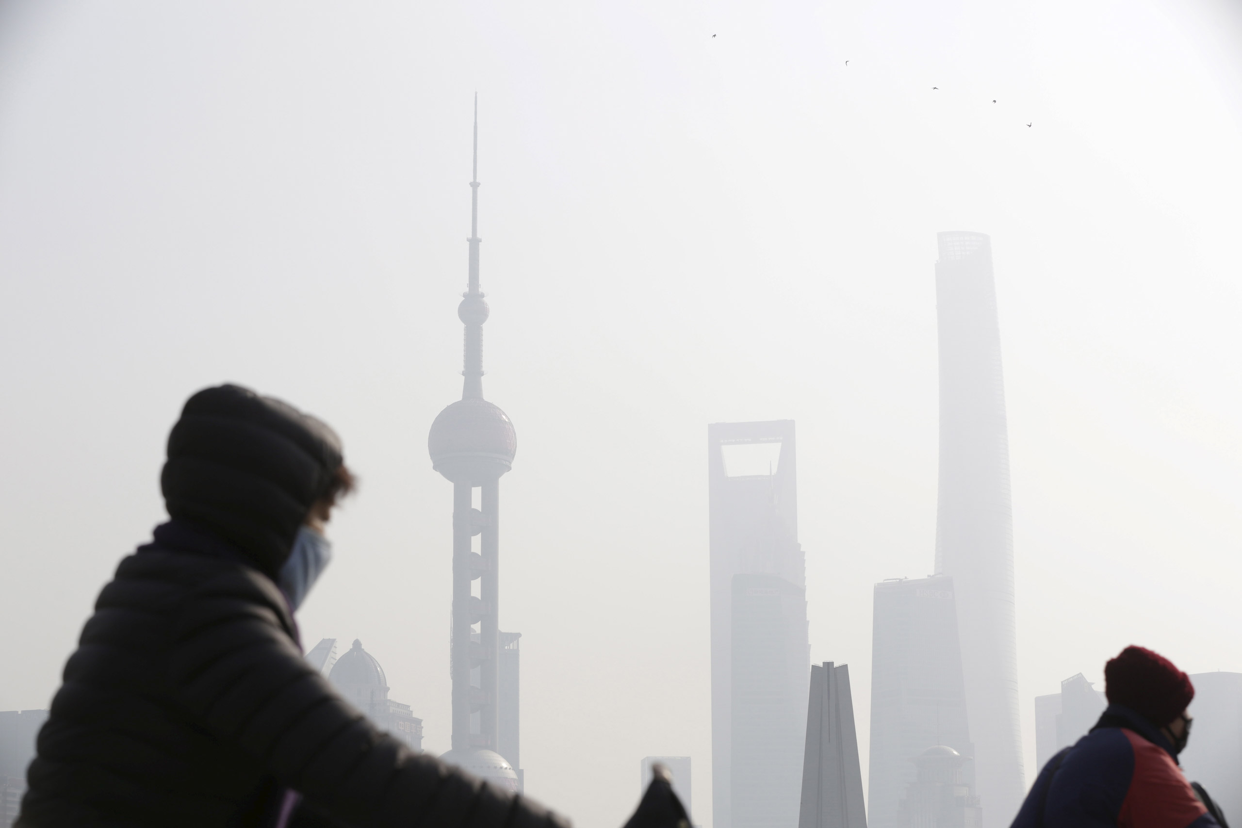 People wear protective masks near the Bund during a polluted day in Shanghai, China, January 19, 2016. Air pollution levels fell in most cities in China last year, environmental group Greenpeace said on Wednesday, but a humid and windless winter shrouded