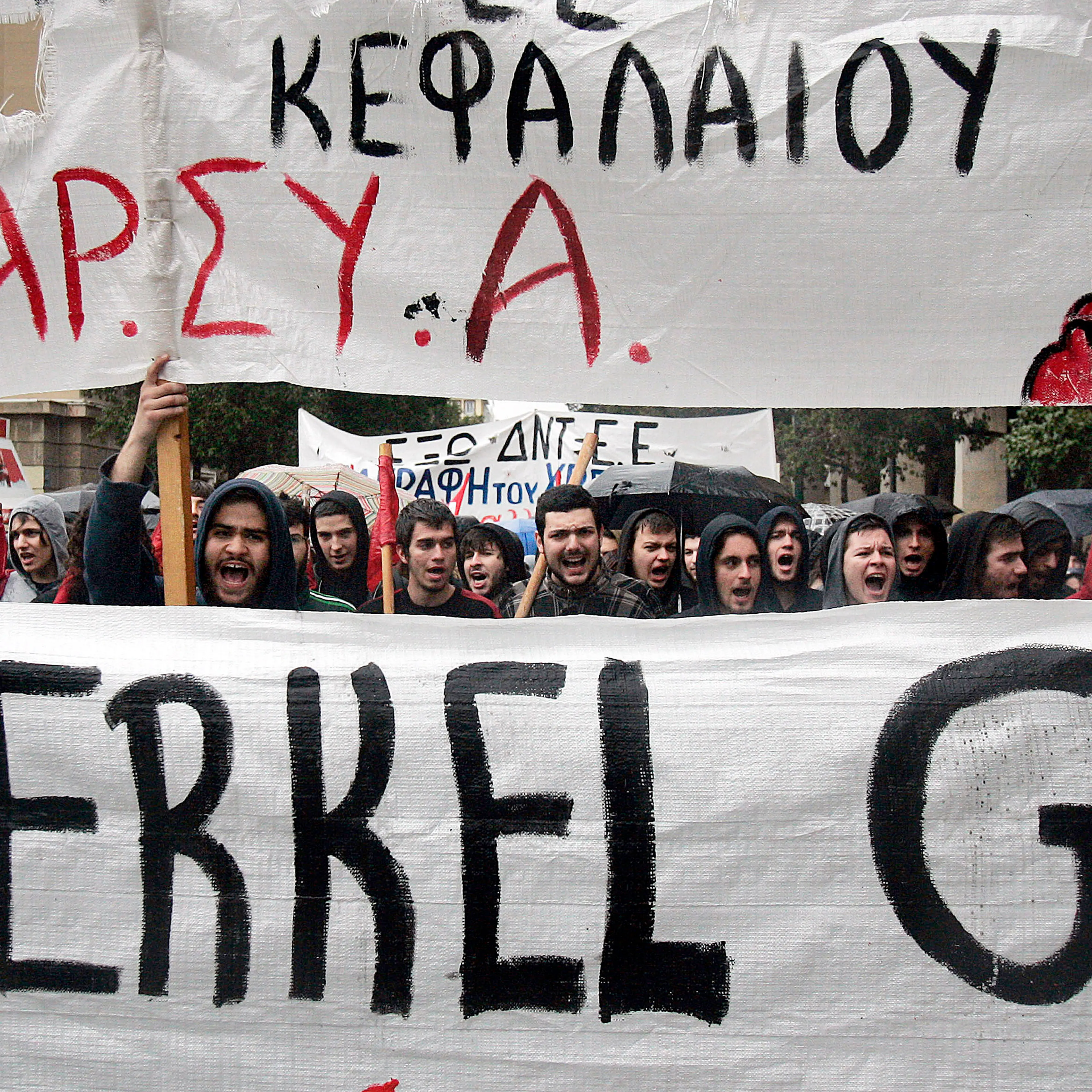 Protesters hold a banner as they march during a demonstration against the visit of Germany's Chancellor Angela Merkel on April 11, 2014 in Athens.