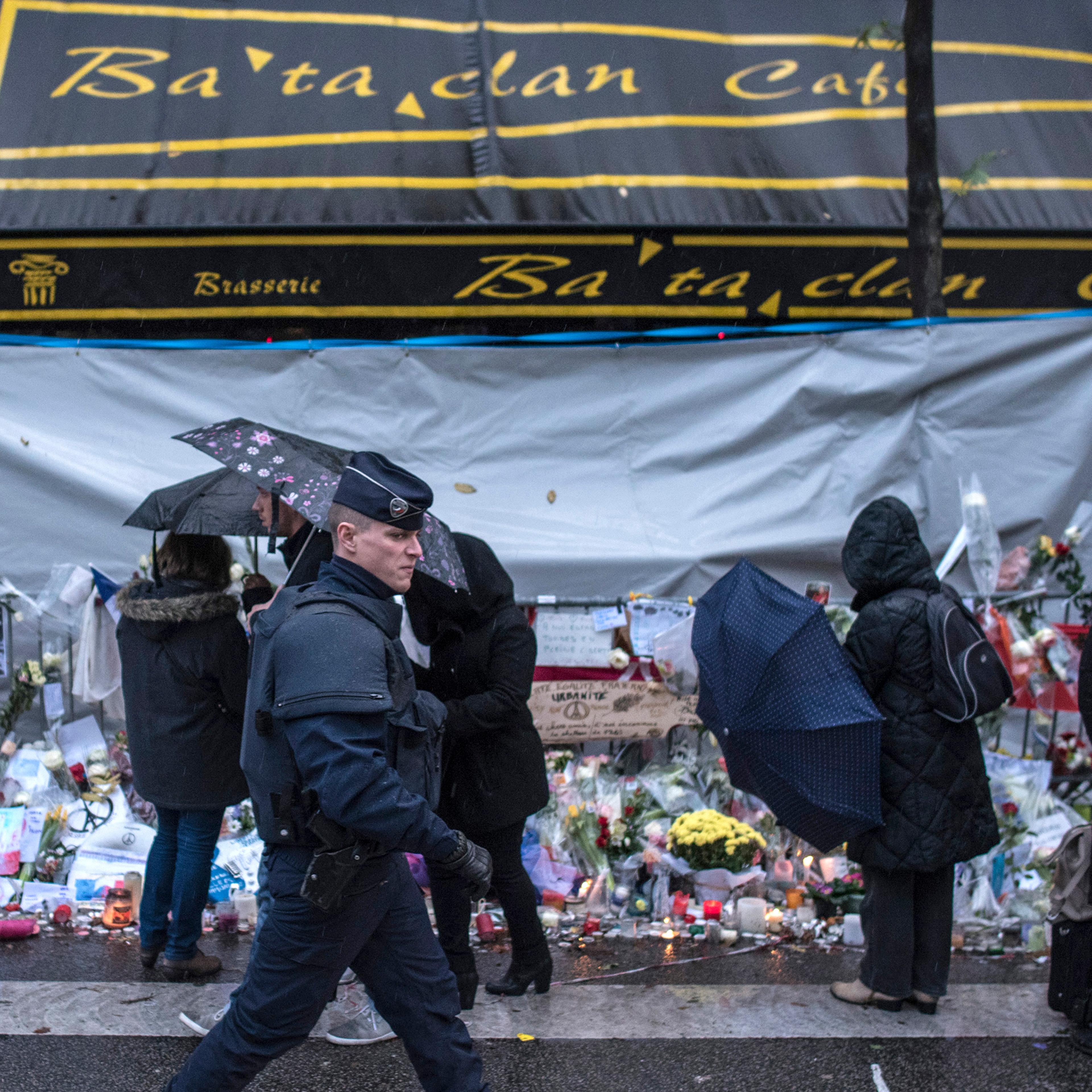 A policeman walks by as people pay respects to victims of the Paris attacks in front of the Bataclan concert hall, where 89 people were massacred, Nov. 25, 2015.