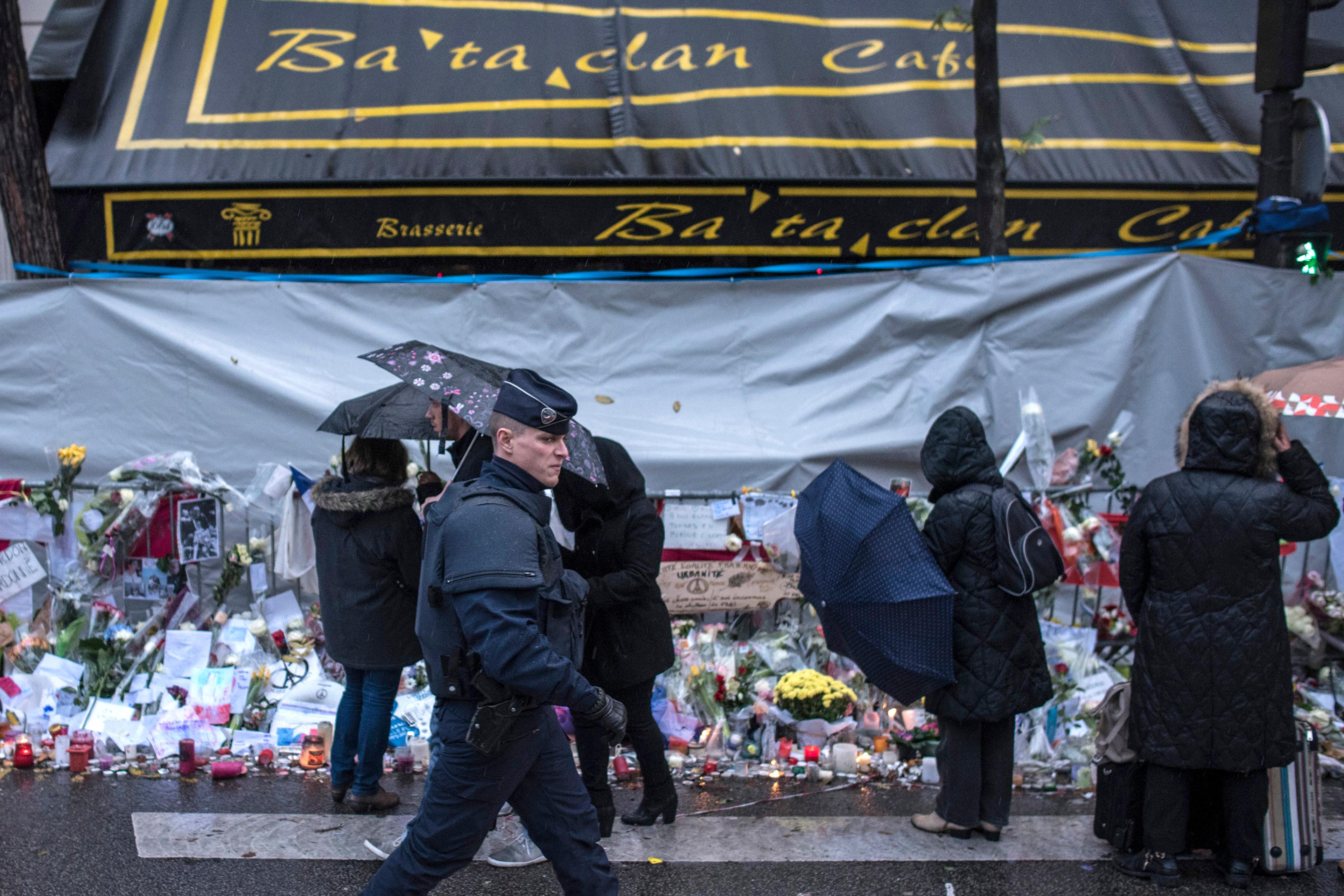 A policeman walks by as people pay respects to victims of the Paris attacks in front of the Bataclan concert hall, where 89 people were massacred, Nov. 25, 2015.