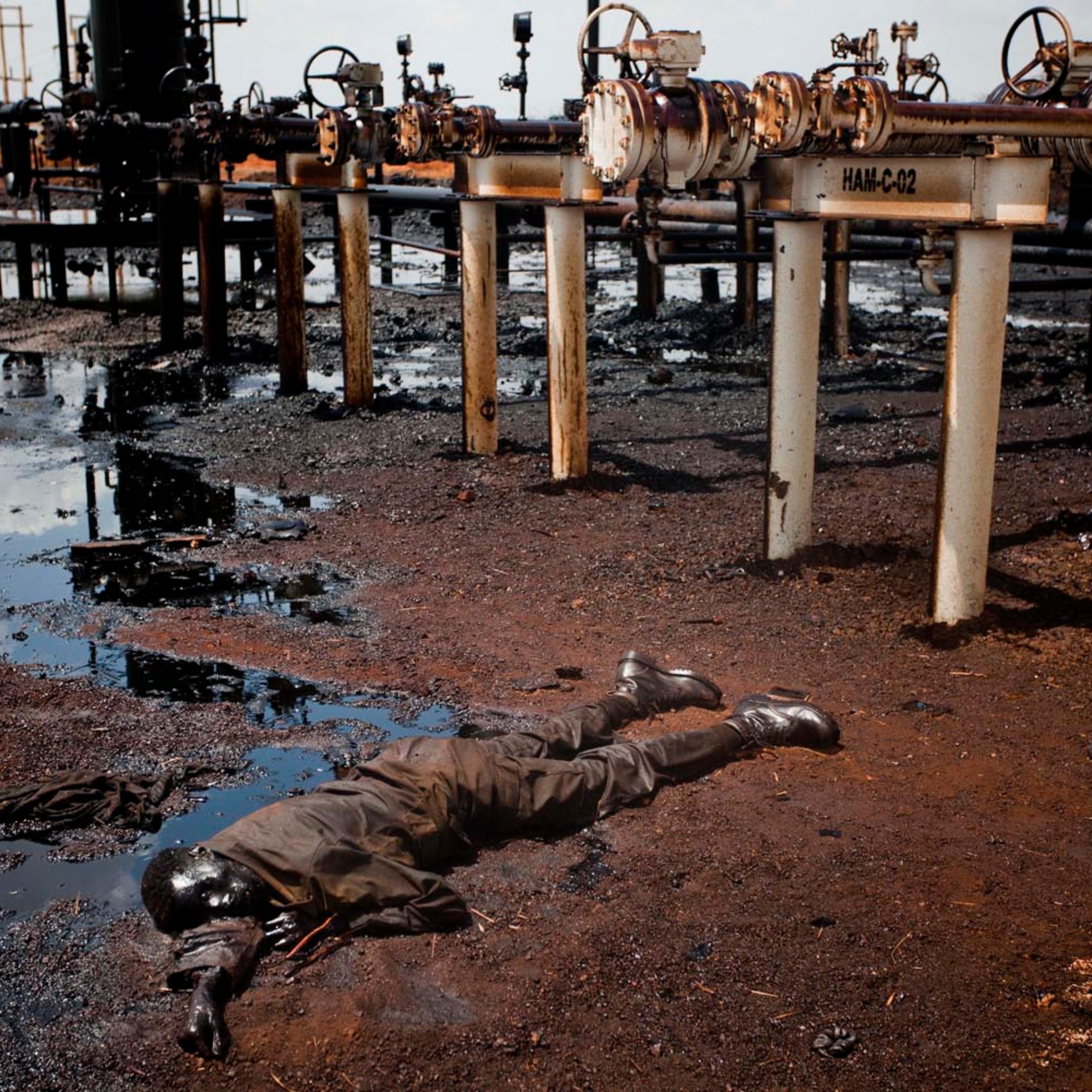A soldier of the northern regime's army, the Sudan Armed Forces (SAF), lies dead, immersed in oil next to a leaking petroleum facility after heavy fighting with southern SPLA troops after they entered Heglig in mid April.
