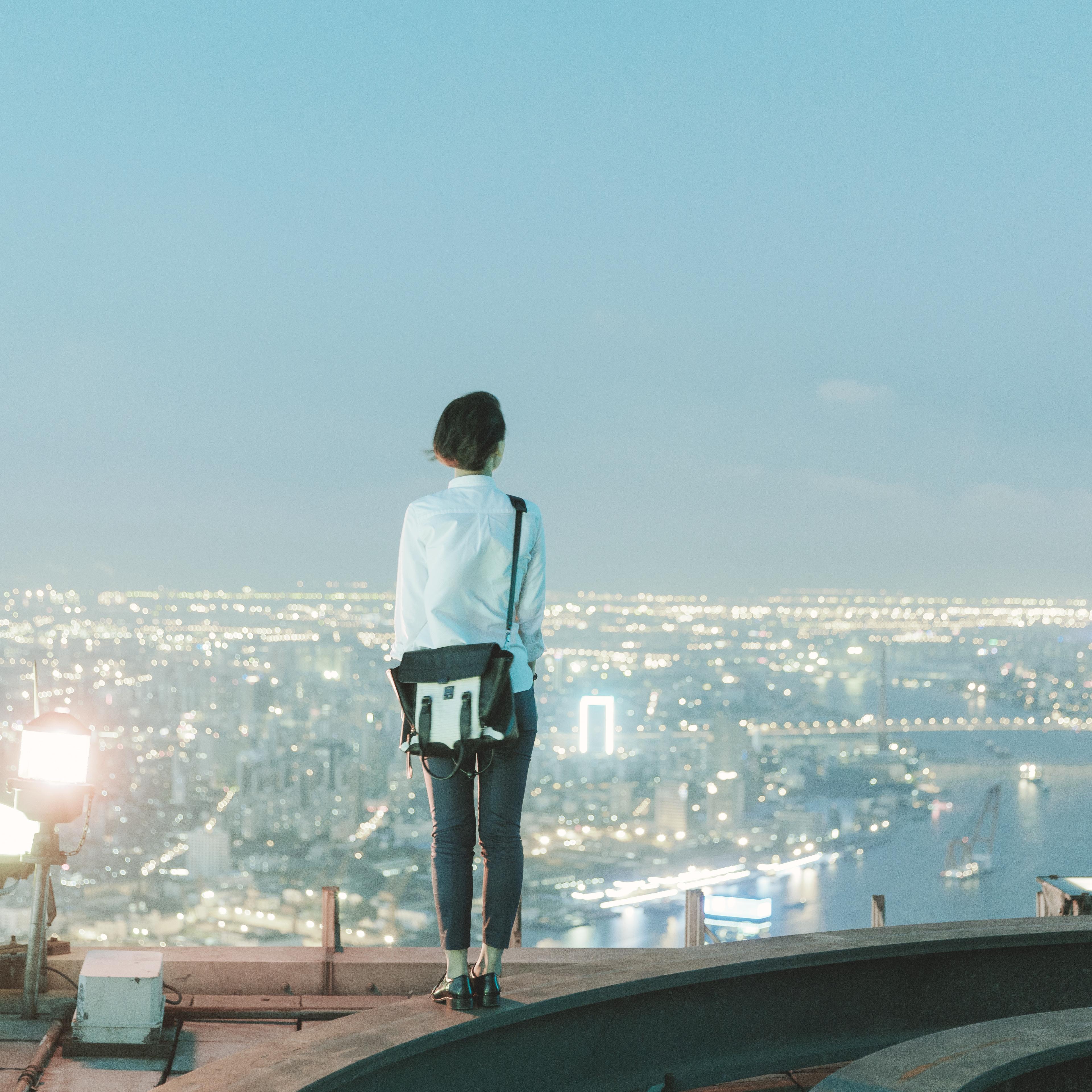 woman-standing-rooftop-rear-view-city
