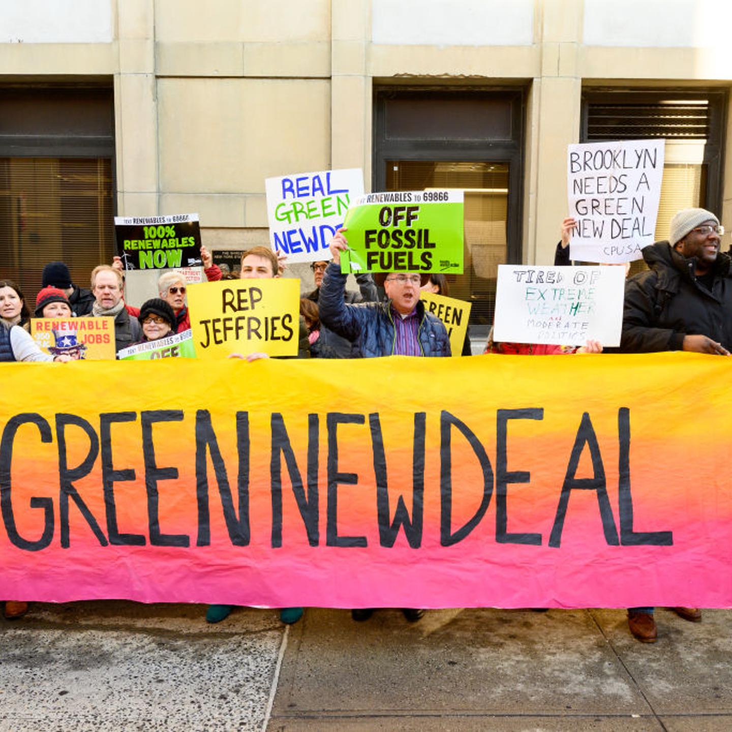 Demonstrators seen holding a huge banner saying, green new