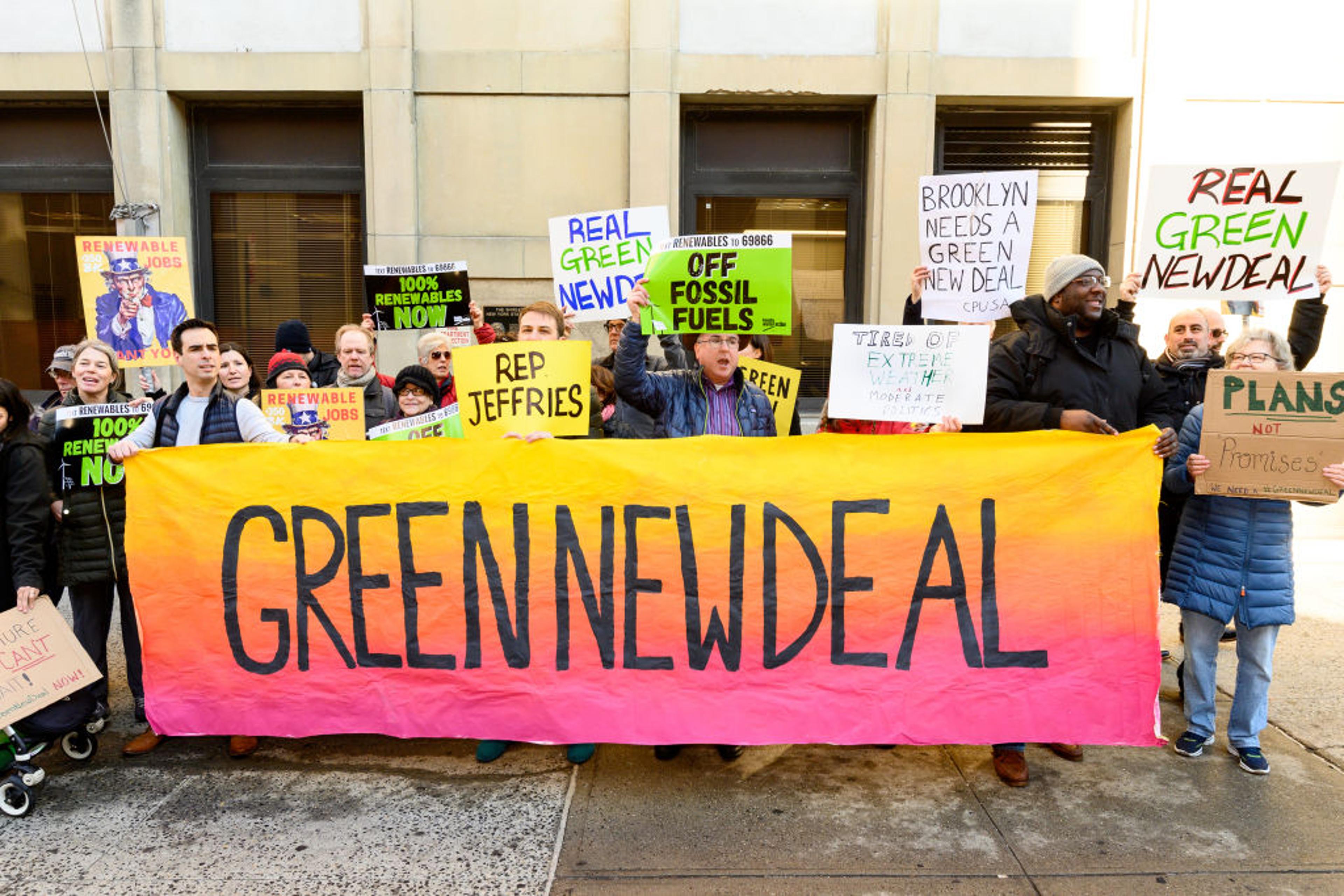 Demonstrators seen holding a huge banner saying, green new