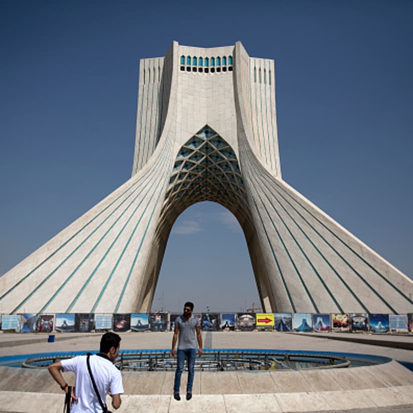 An Iranian tourist poses for a photograph in front of the Azadi tower in Tehran, Iran, on Friday, Aug. 21, 2015.