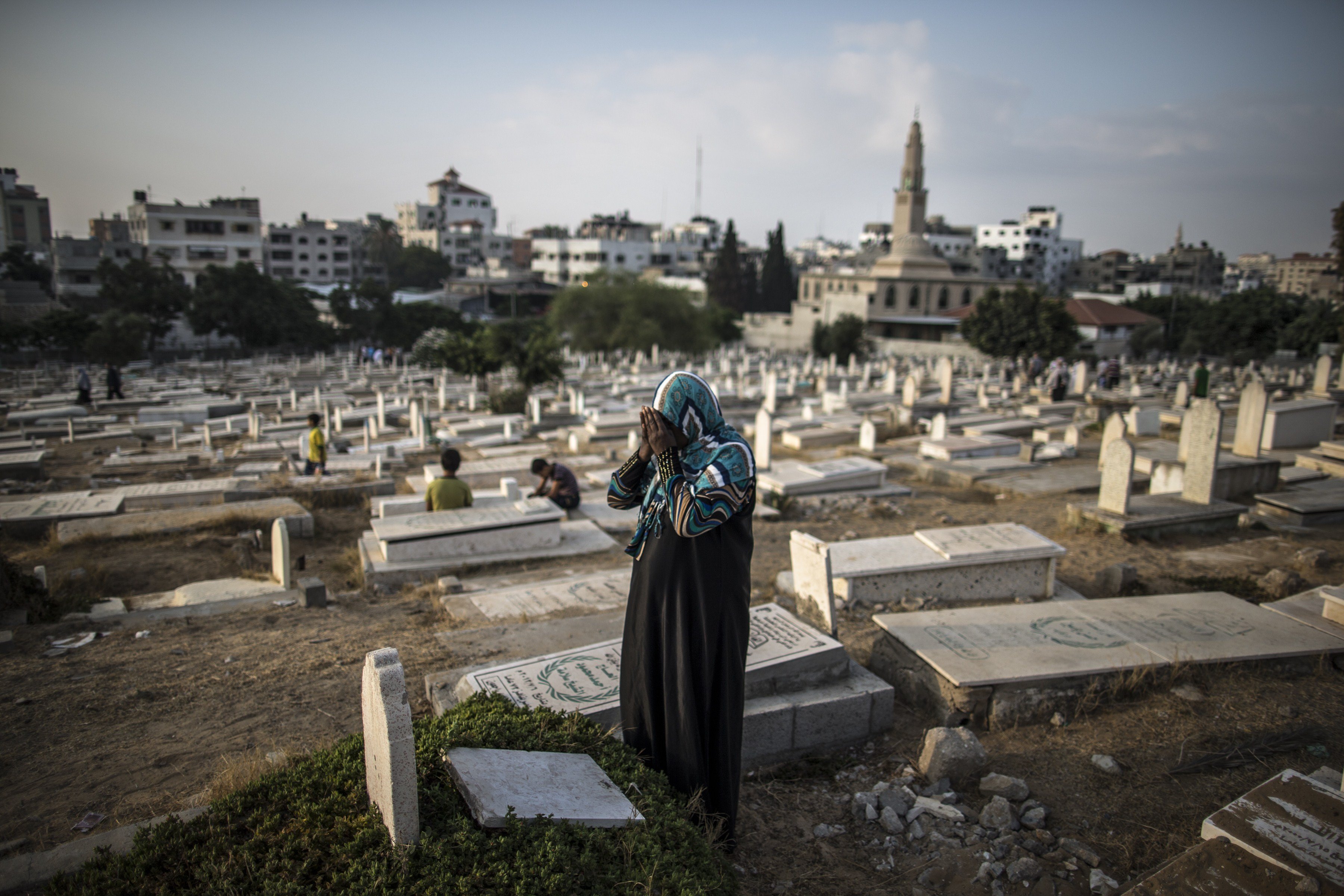 A Palestinian woman prays over the grave of a relative at Sheikh Radwan cemetery, northwest of Gaza City on July 28, 2014 on the first day of Eid al-Fitr.
