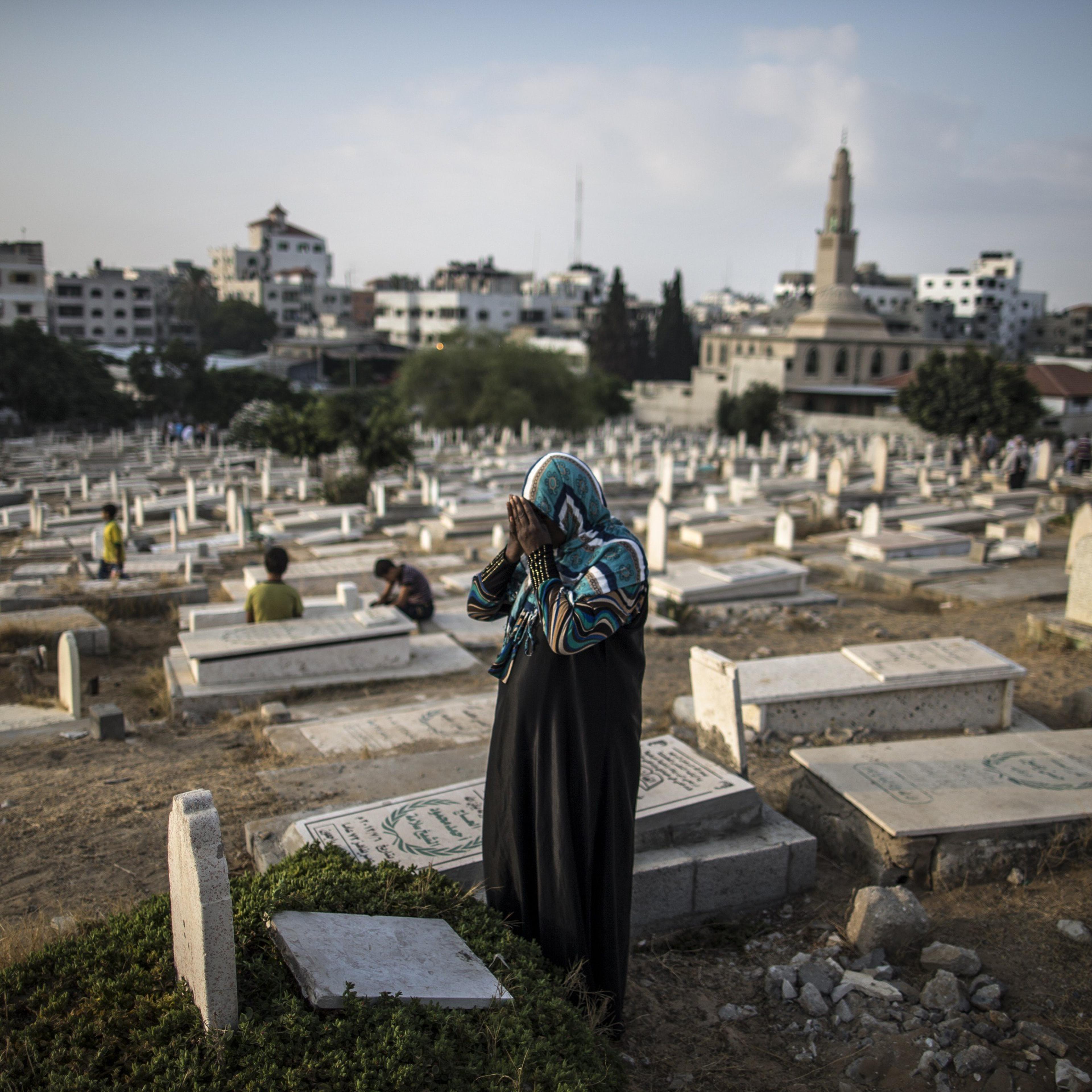 A Palestinian woman prays over the grave of a relative at Sheikh Radwan cemetery, northwest of Gaza City on July 28, 2014 on the first day of Eid al-Fitr.