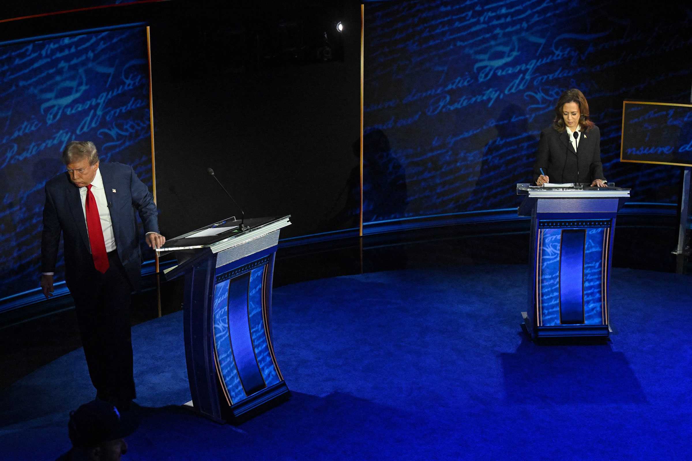 Former President and Republican presidential candidate Donald Trump walks away during a commercial break as Vice President and Democratic presidential candidate Kamala Harris take notes during a presidential debate at the National Constitution Center in 
