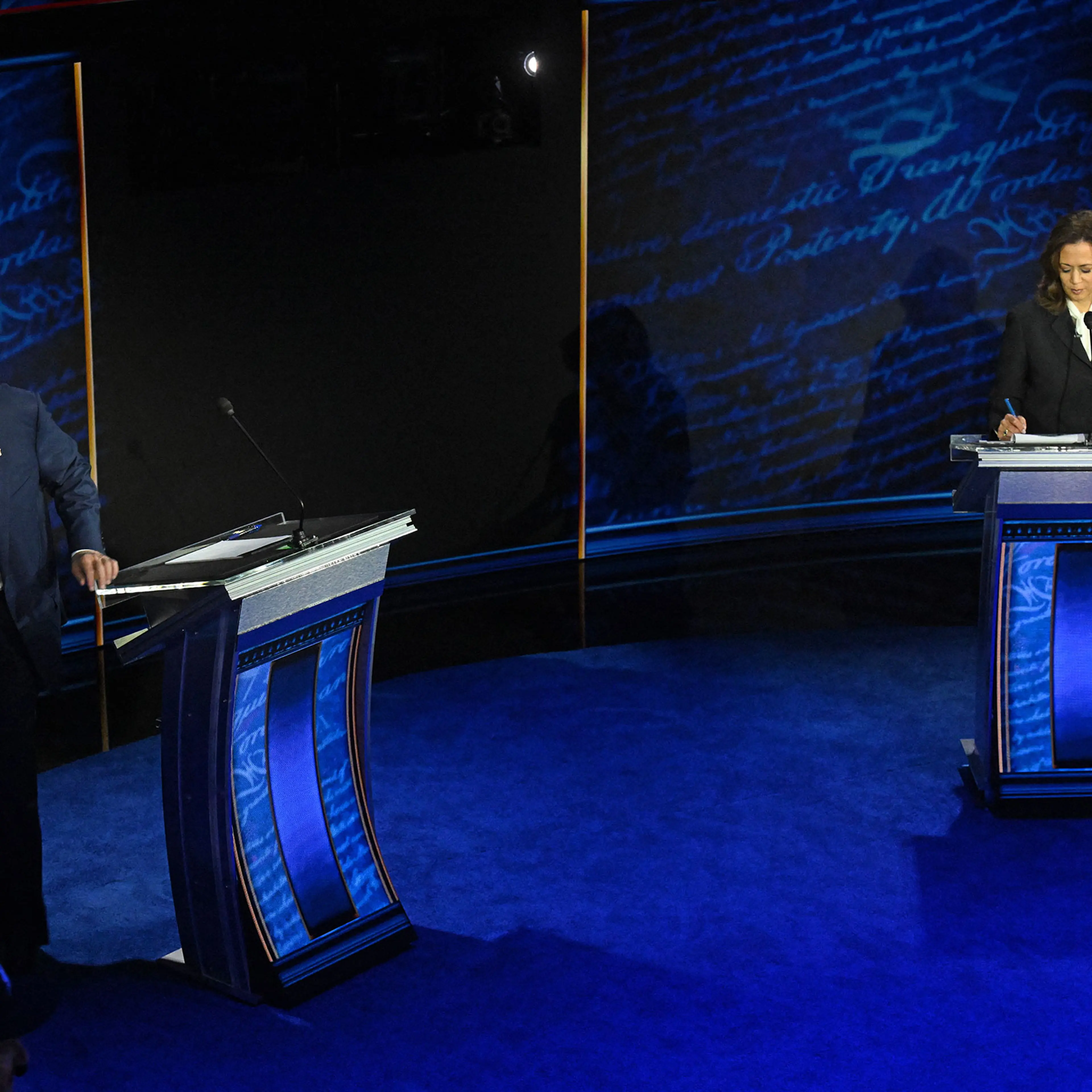 Former President and Republican presidential candidate Donald Trump walks away during a commercial break as Vice President and Democratic presidential candidate Kamala Harris take notes during a presidential debate at the National Constitution Center in