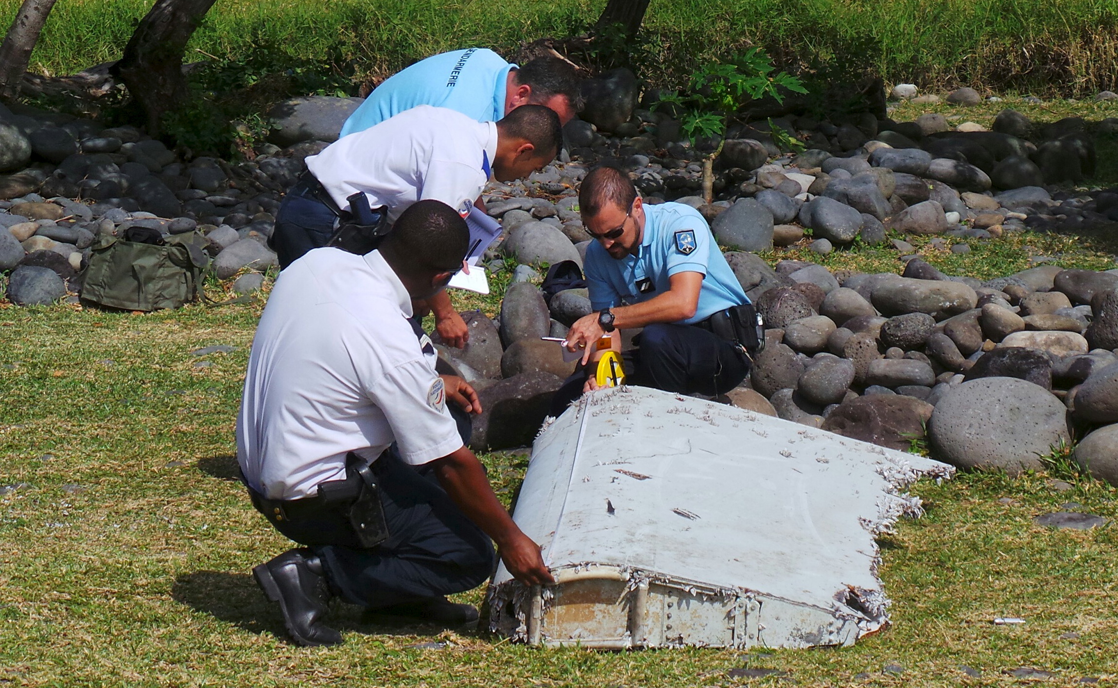 French gendarmes and police inspect a large piece of plane debris which was found on the beach in Saint-Andre, on the French Indian Ocean island of La Reunion