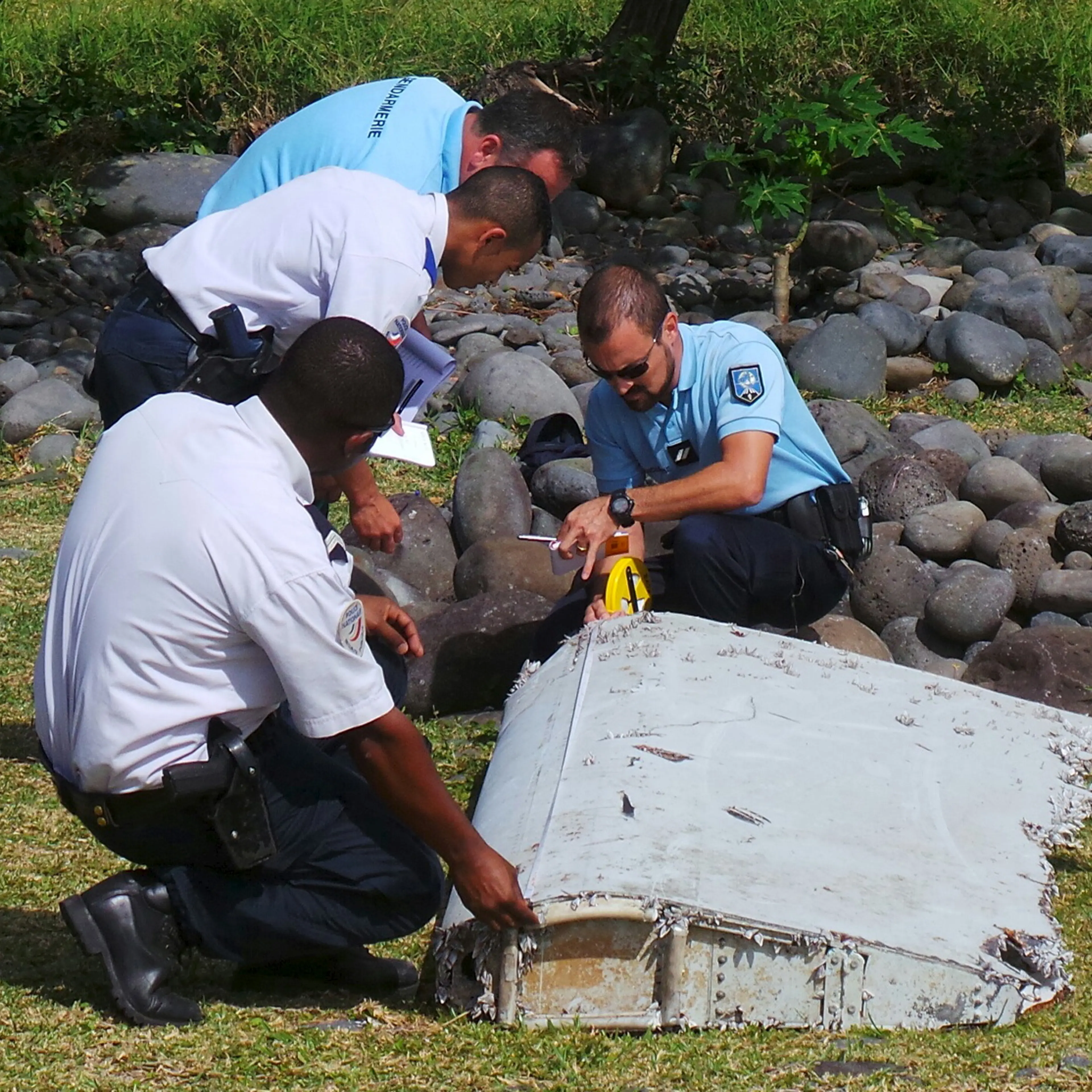 French gendarmes and police inspect a large piece of plane debris which was found on the beach in Saint-Andre, on the French Indian Ocean island of La Reunion