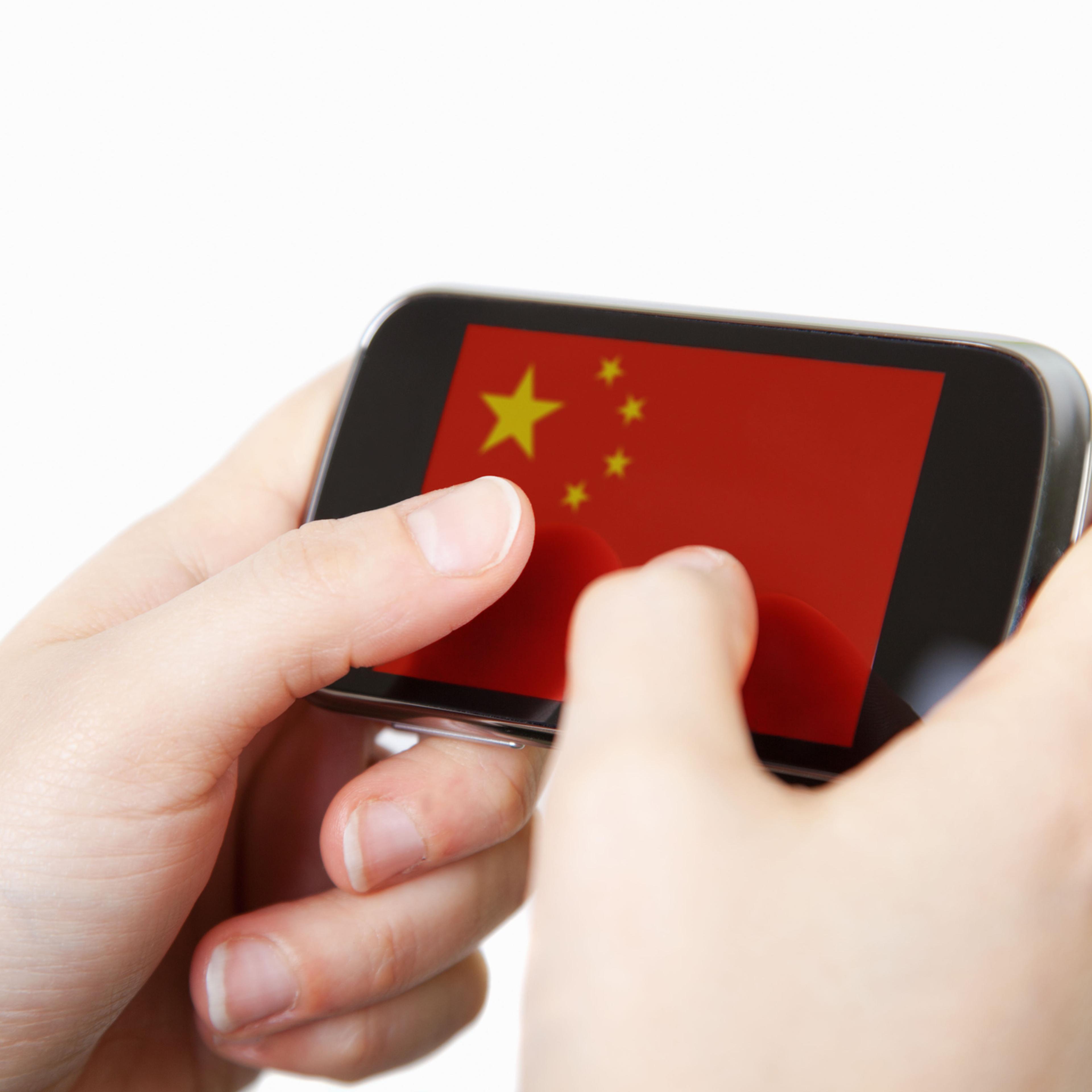 Close up of a human hand holding smart phone with the flag of China in the display.