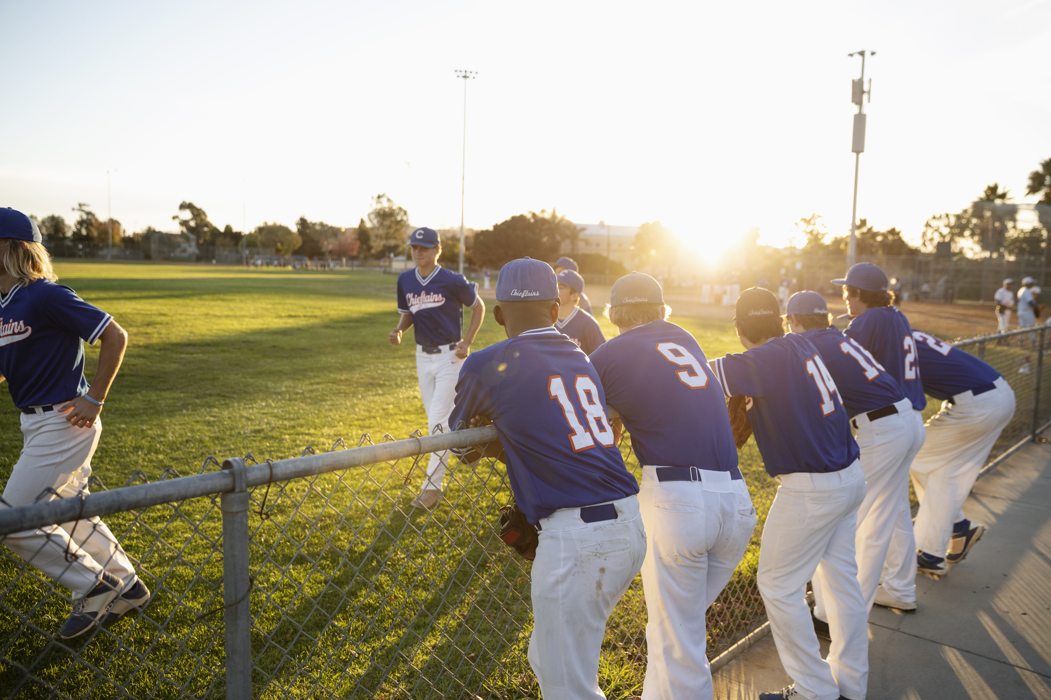 Baseball players at sunny fence