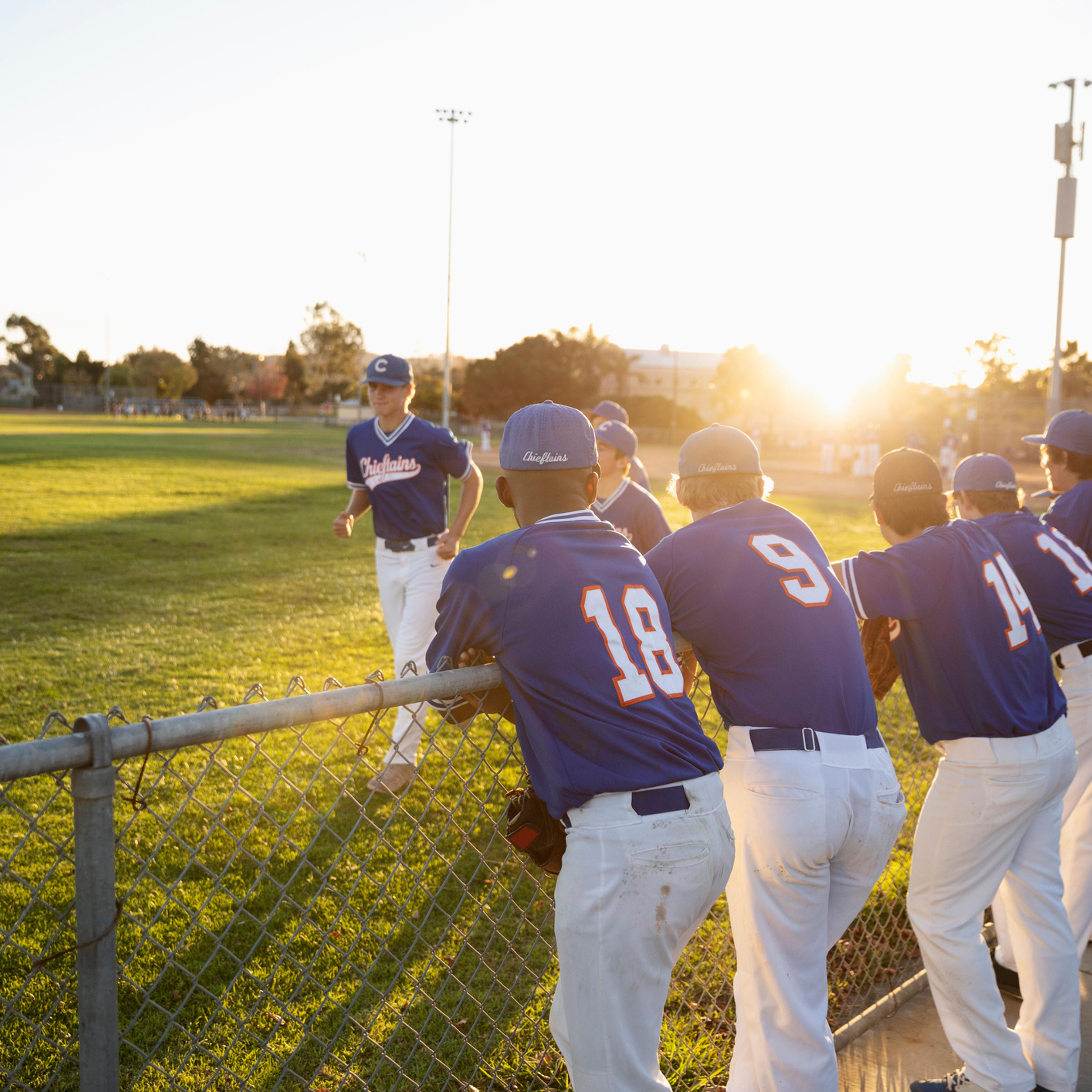 Baseball players at sunny fence