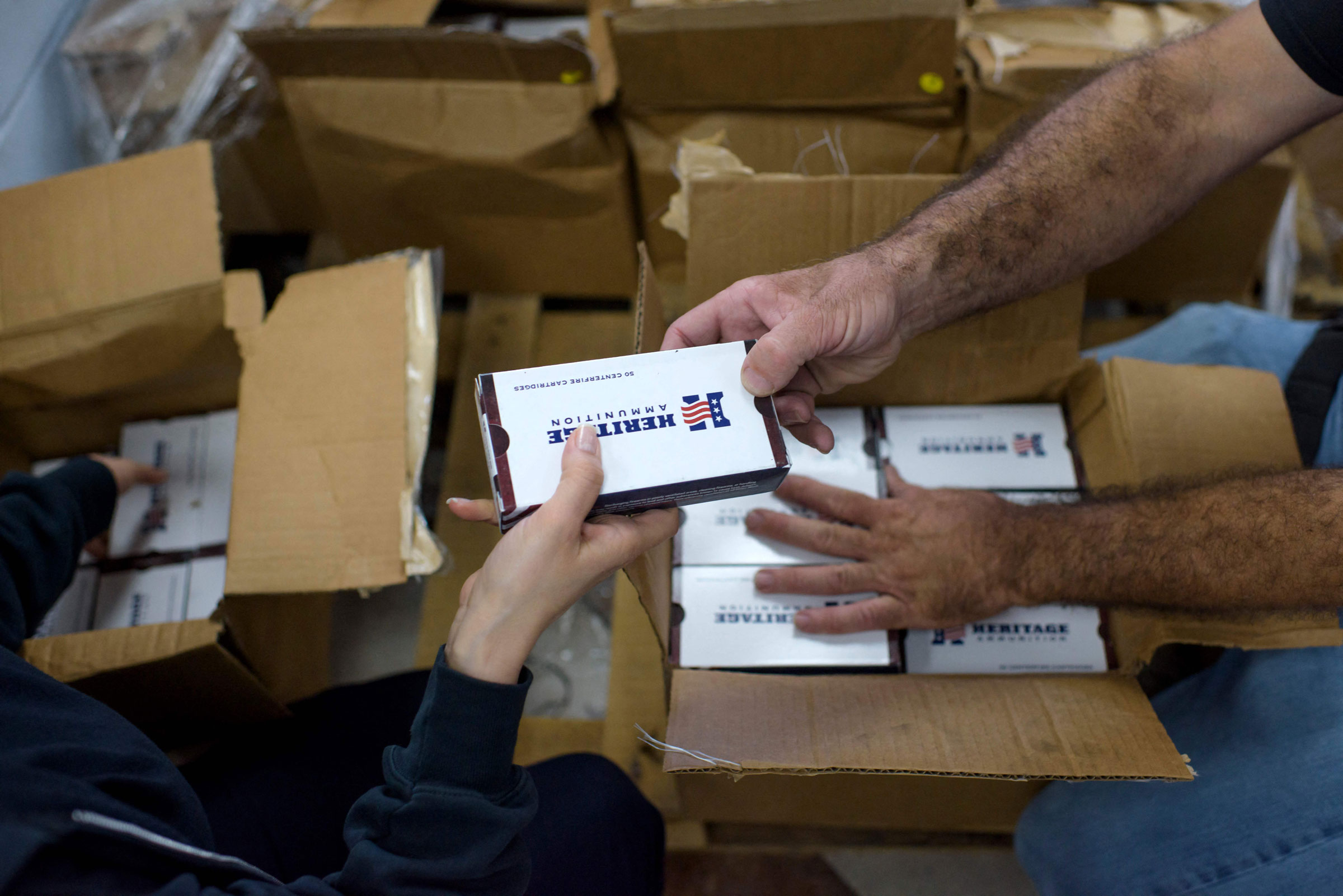 Gorety Mejia (L) hands ammunition to employee Curt Hubbard (R) at Full Armor Firearms