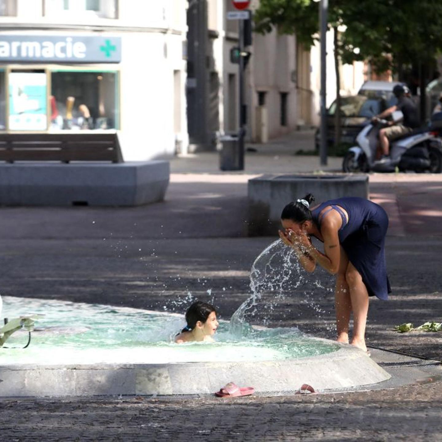People cool off at a water fountain in Perpignan, a city in southern France on June 17, 2022, amid sweltering temperatures.