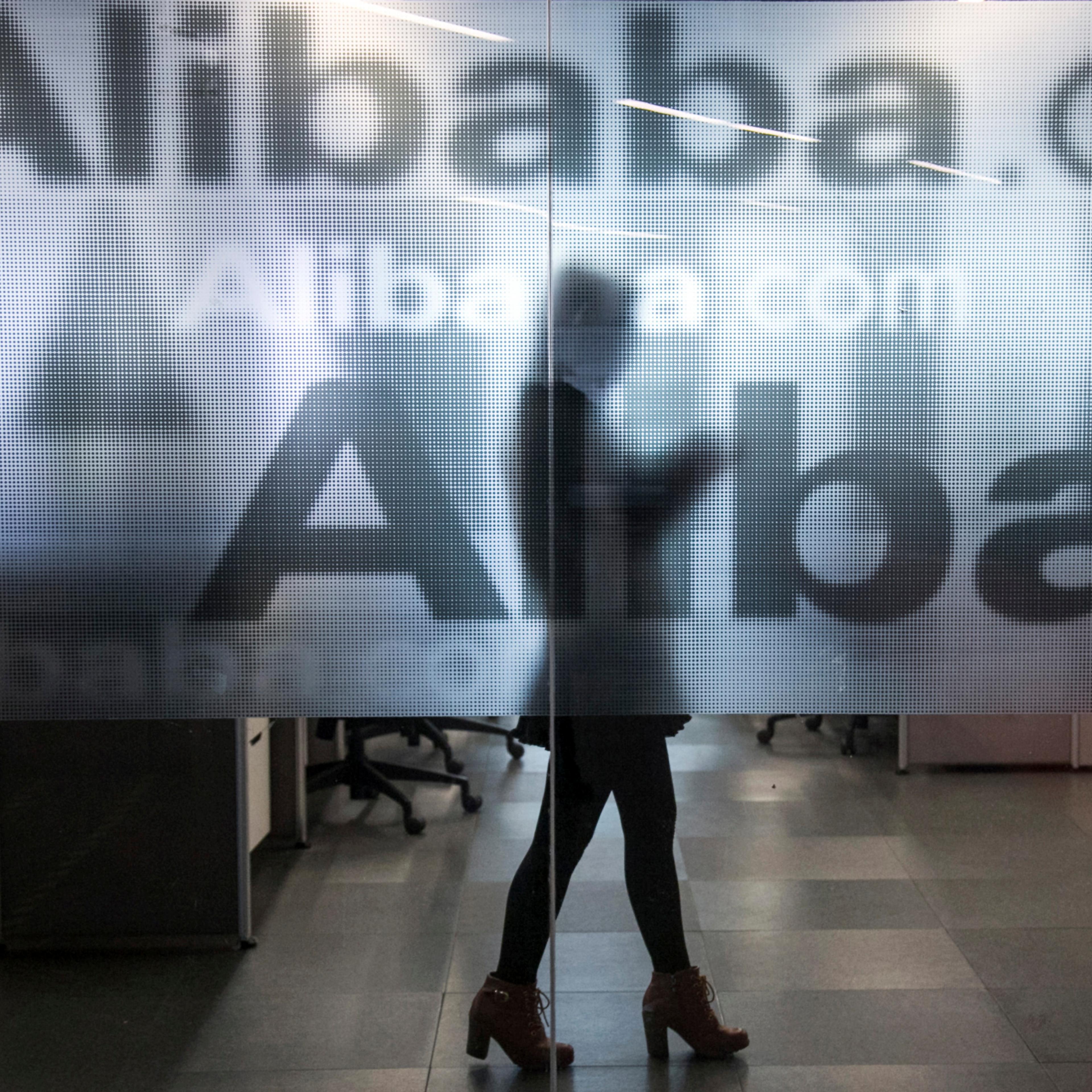 An employee is seen behind a glass wall with the logo of Alibaba at the company's headquarters on the outskirts of Hangzhou, Zhejiang province