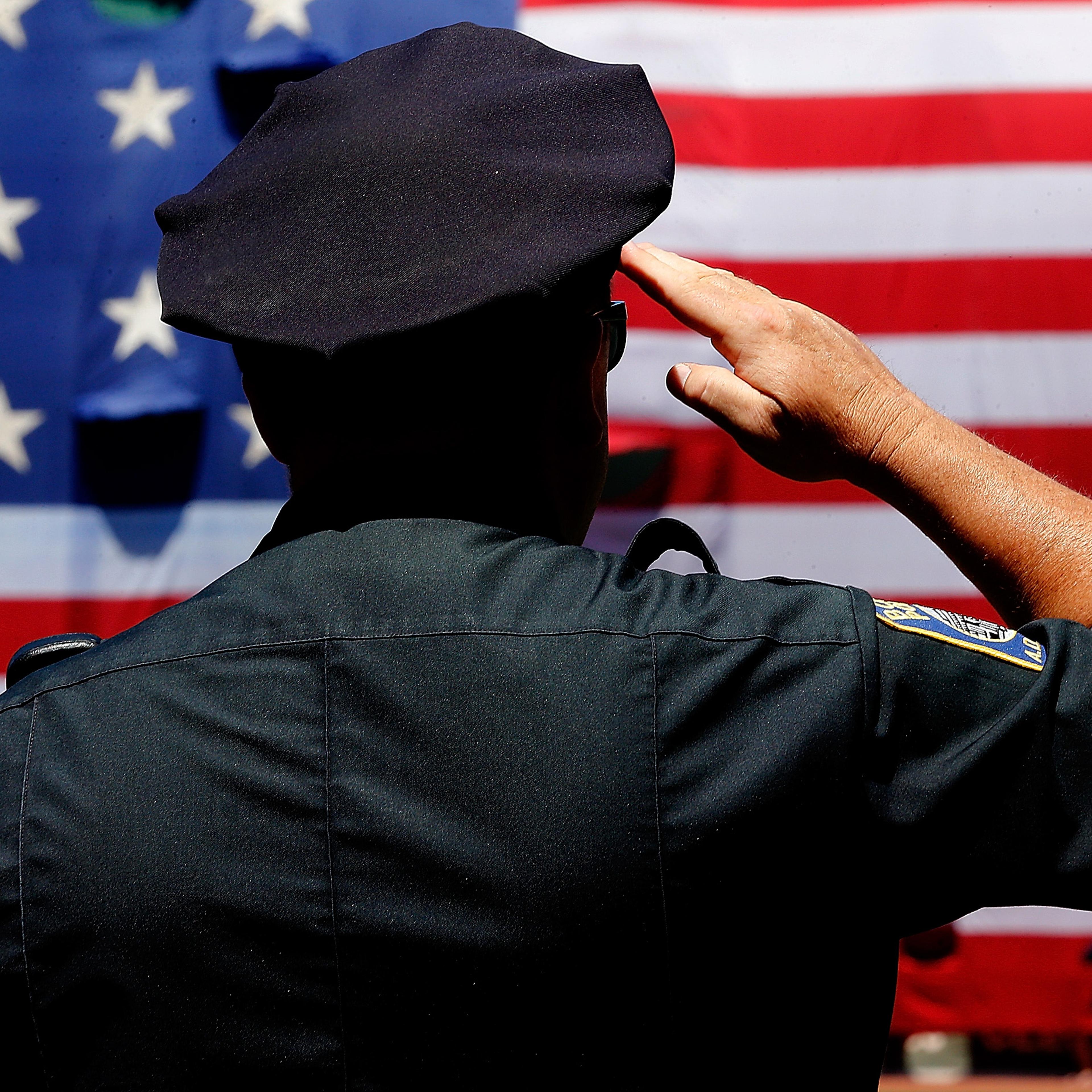 A police officer salutes during the National Anthem before the first game of a doubleheader between the Baltimore Orioles and the Boston Red Sox at Fenway Park on July 5, 2014 in Boston.