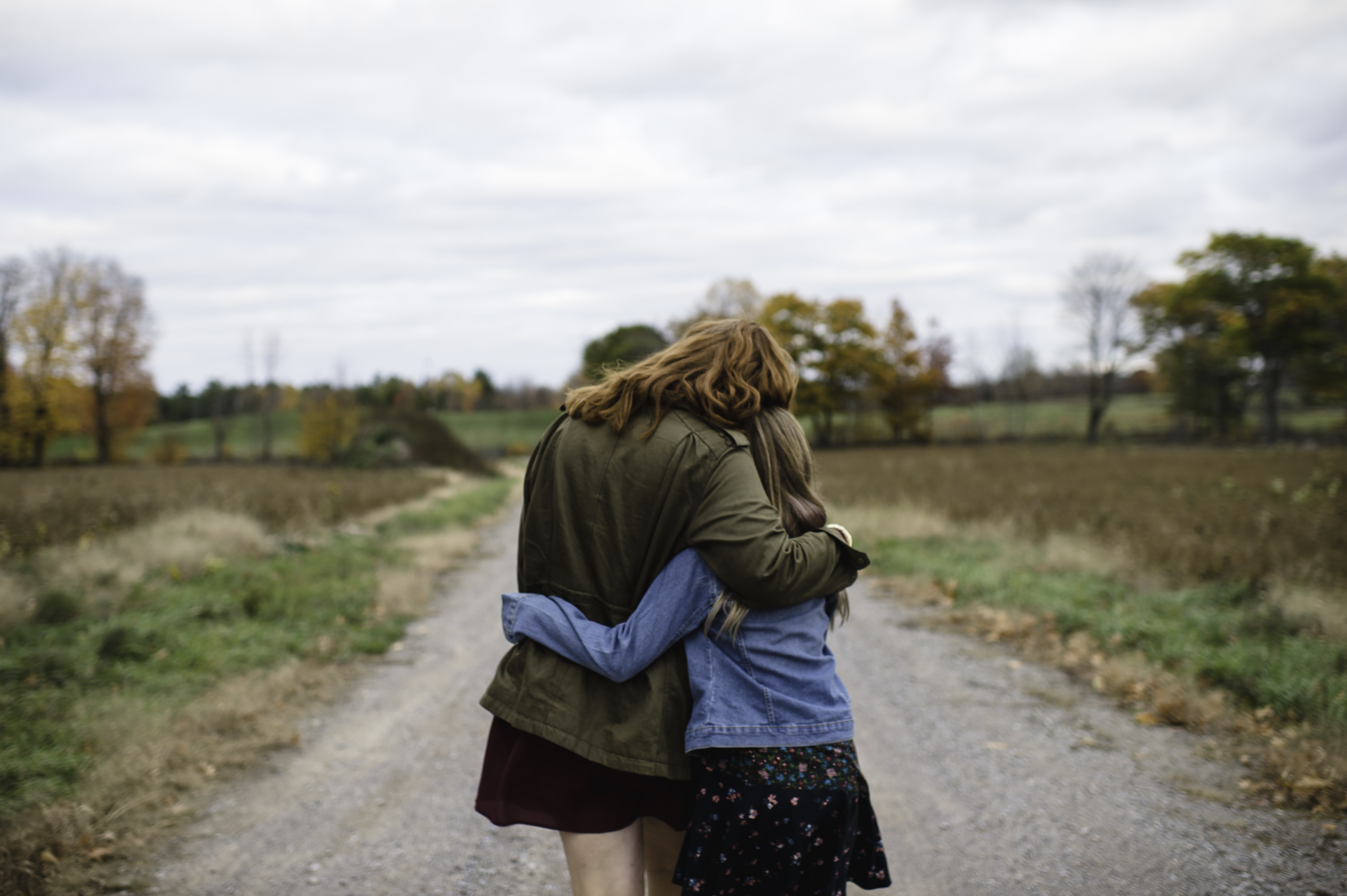 Mother and daughter hugging on dirt road, Lakefield, Ontario, Canada
