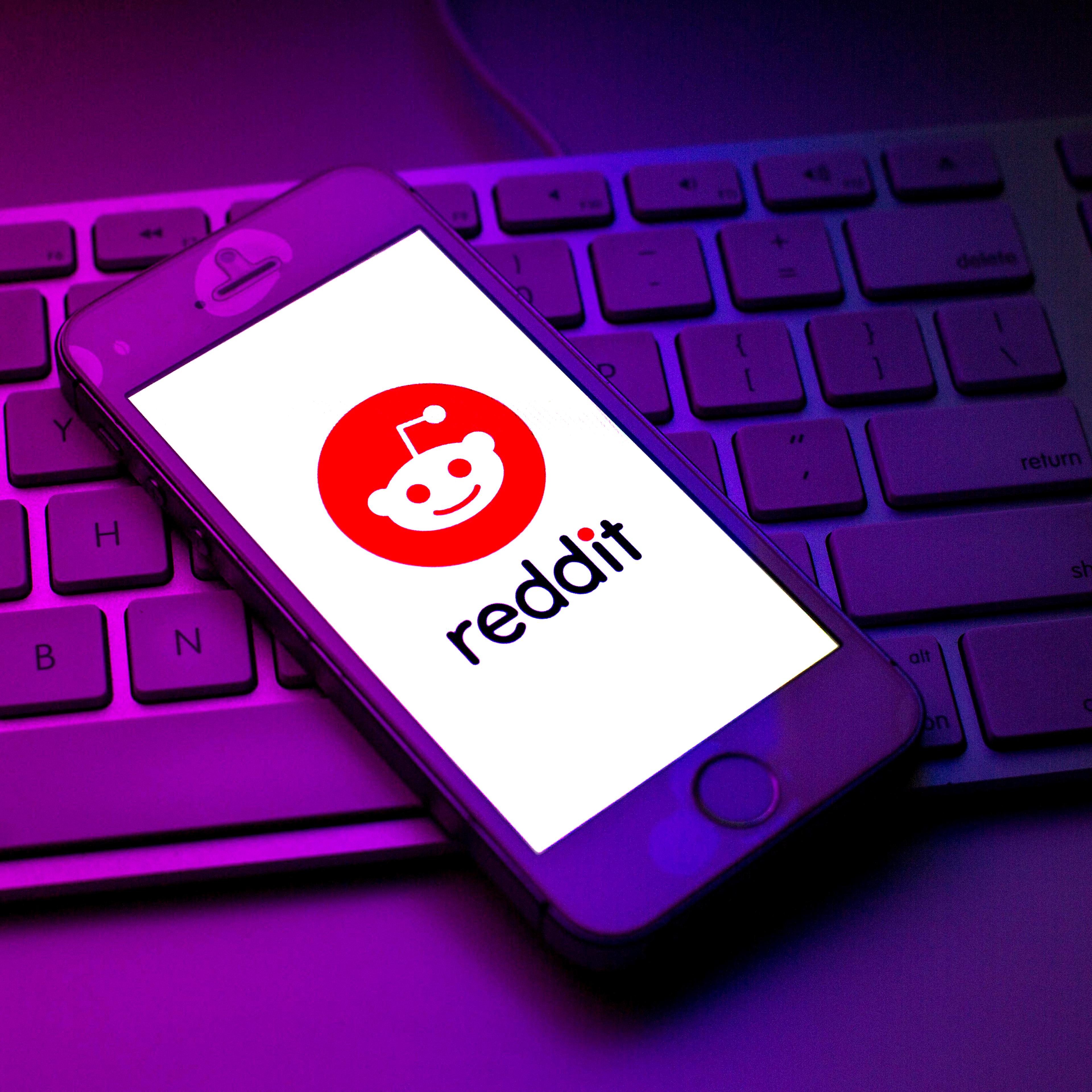 Reddit logo seen displayed on a smartphone on top of a computer keyboard.