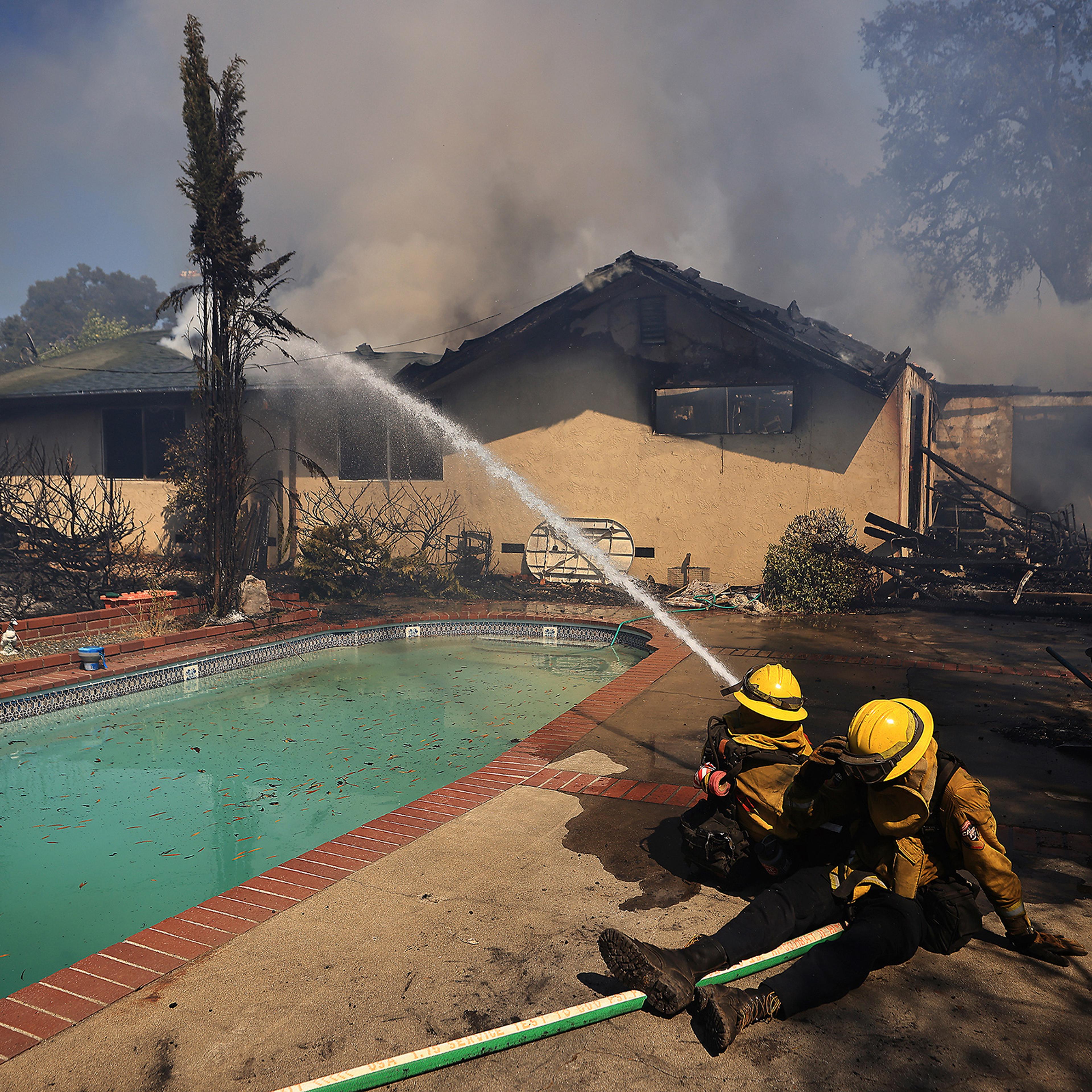 Firefighters take a defensive stand against a home burning in Redwood Valley, Calif., ignited by an 80 acre wind whipped brush fire fed by tinder dry conditions, on July 7.