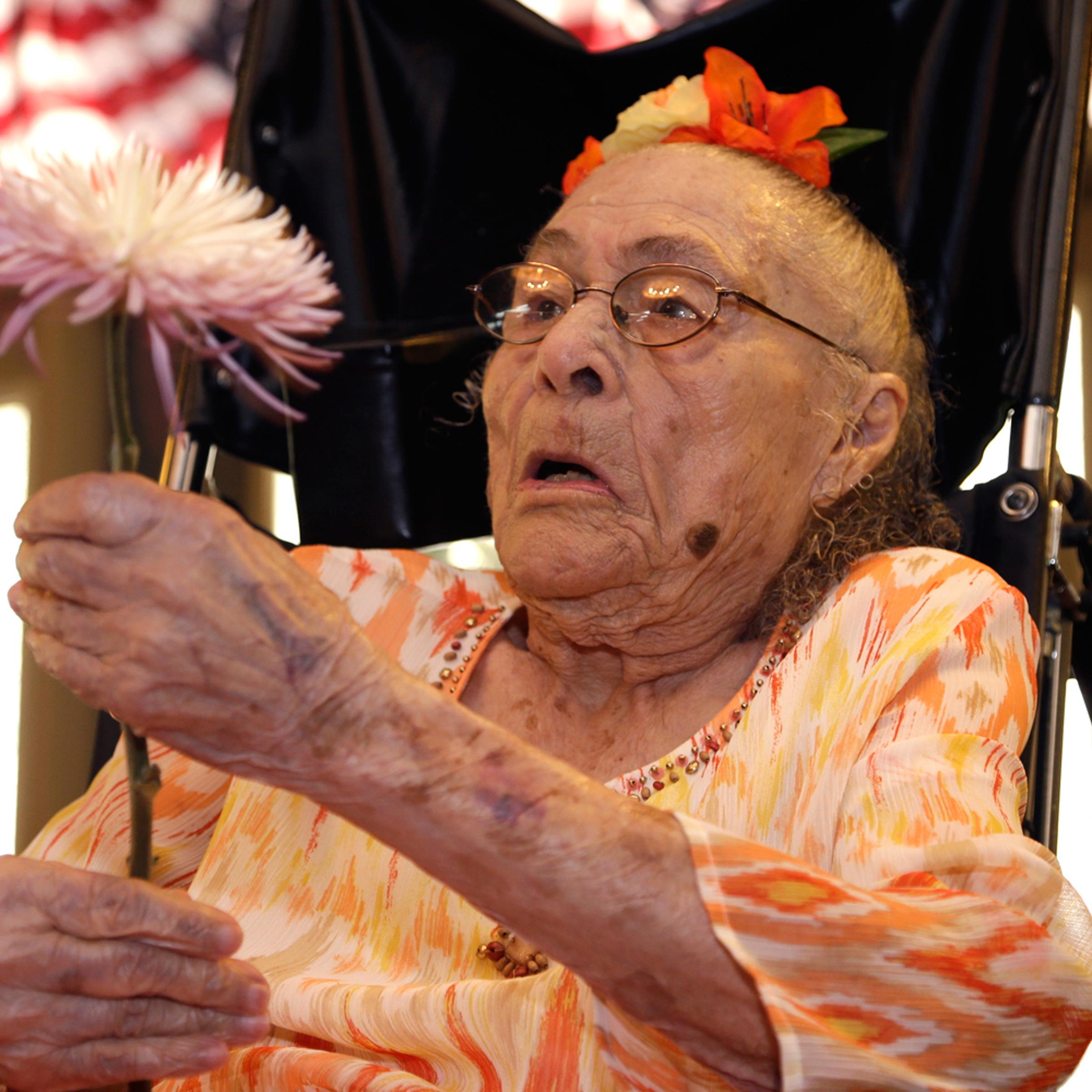 Gertrude Weaver holds a flower given to her a day before her 116th birthday at Silver Oaks Health and Rehabilitation in Camden, Ark on July 3, 2014.