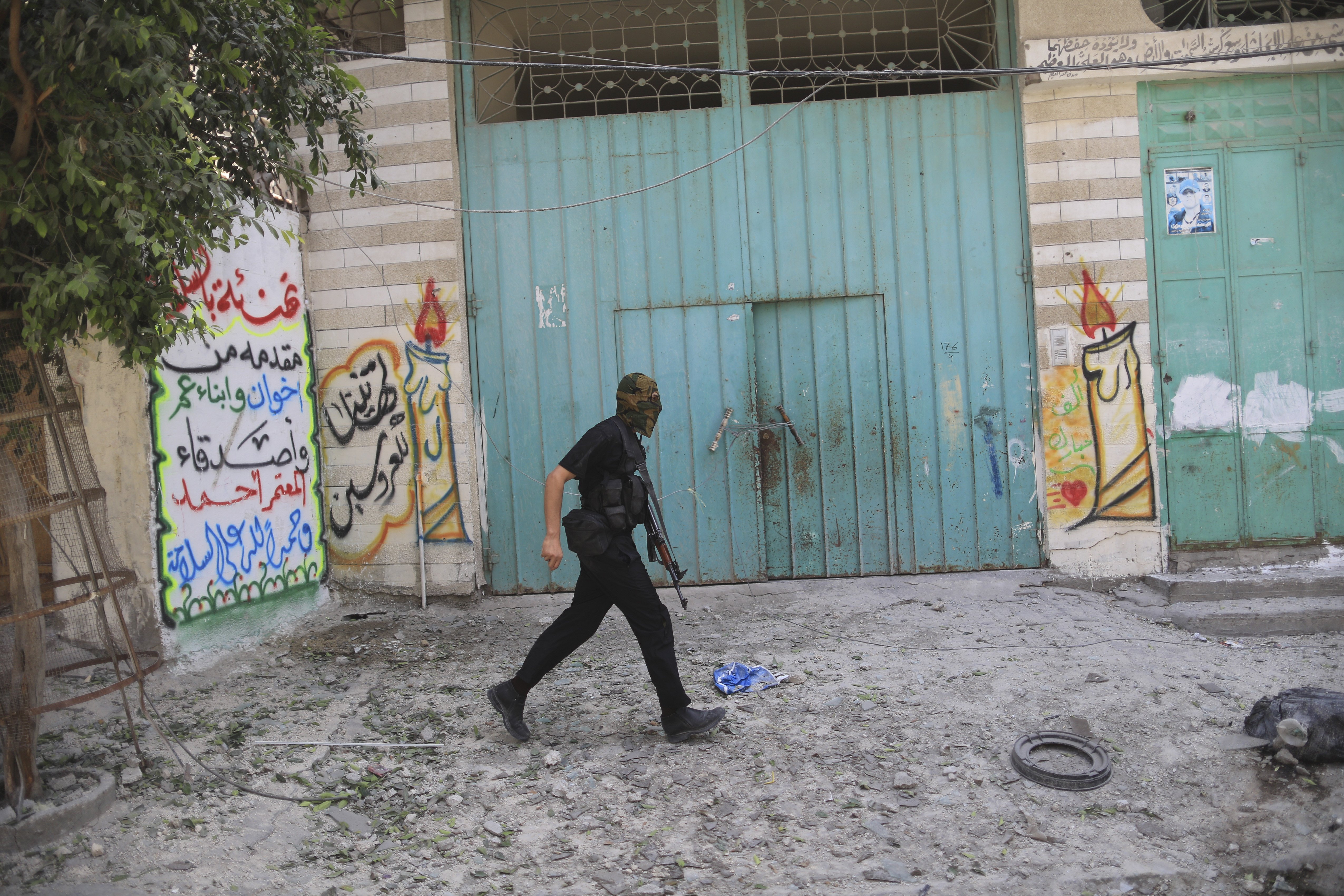 An armed Hamas militant walks through a street in the Shejaiya neighborhood of Gaza City on July 20, 2014.