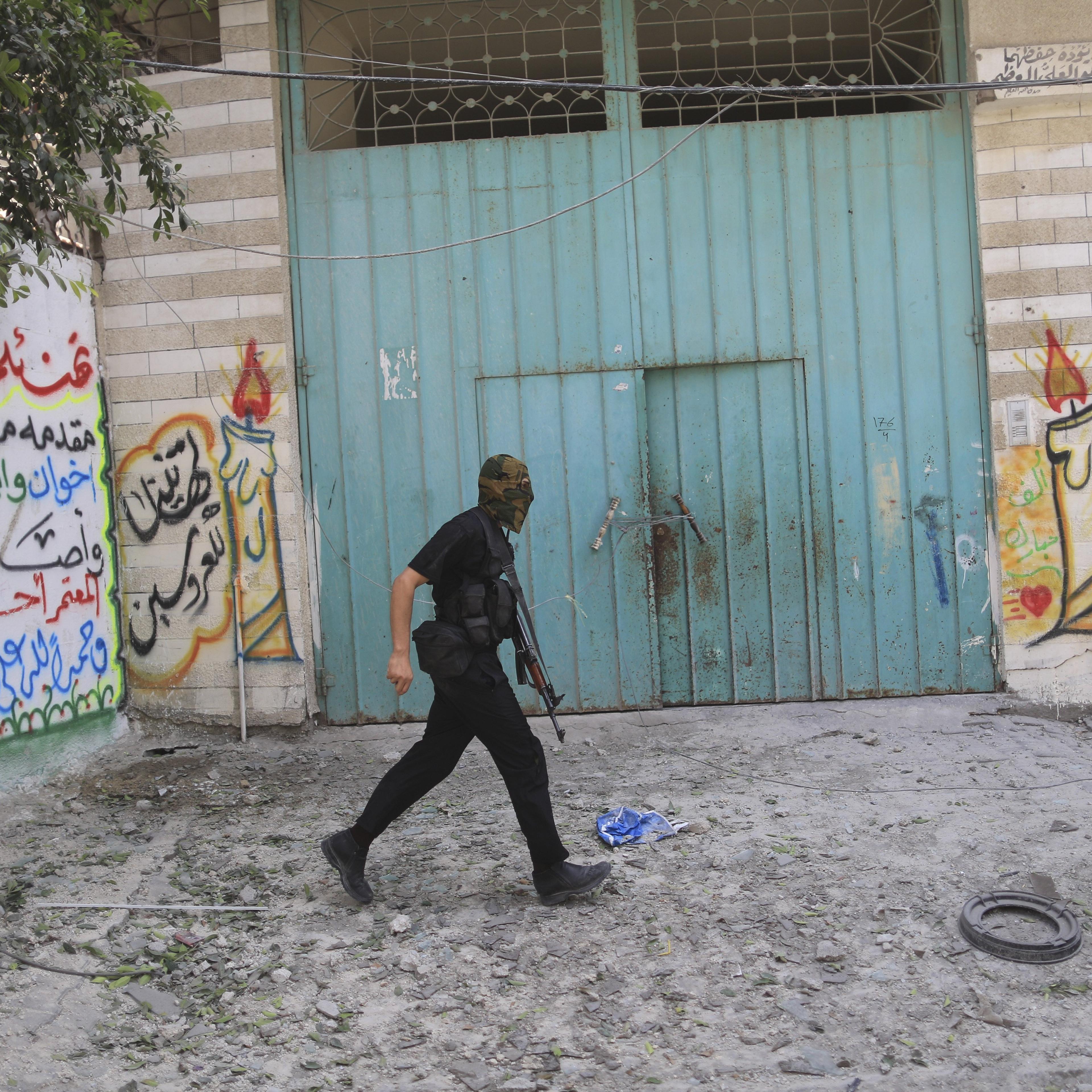 An armed Hamas militant walks through a street in the Shejaiya neighborhood of Gaza City on July 20, 2014.