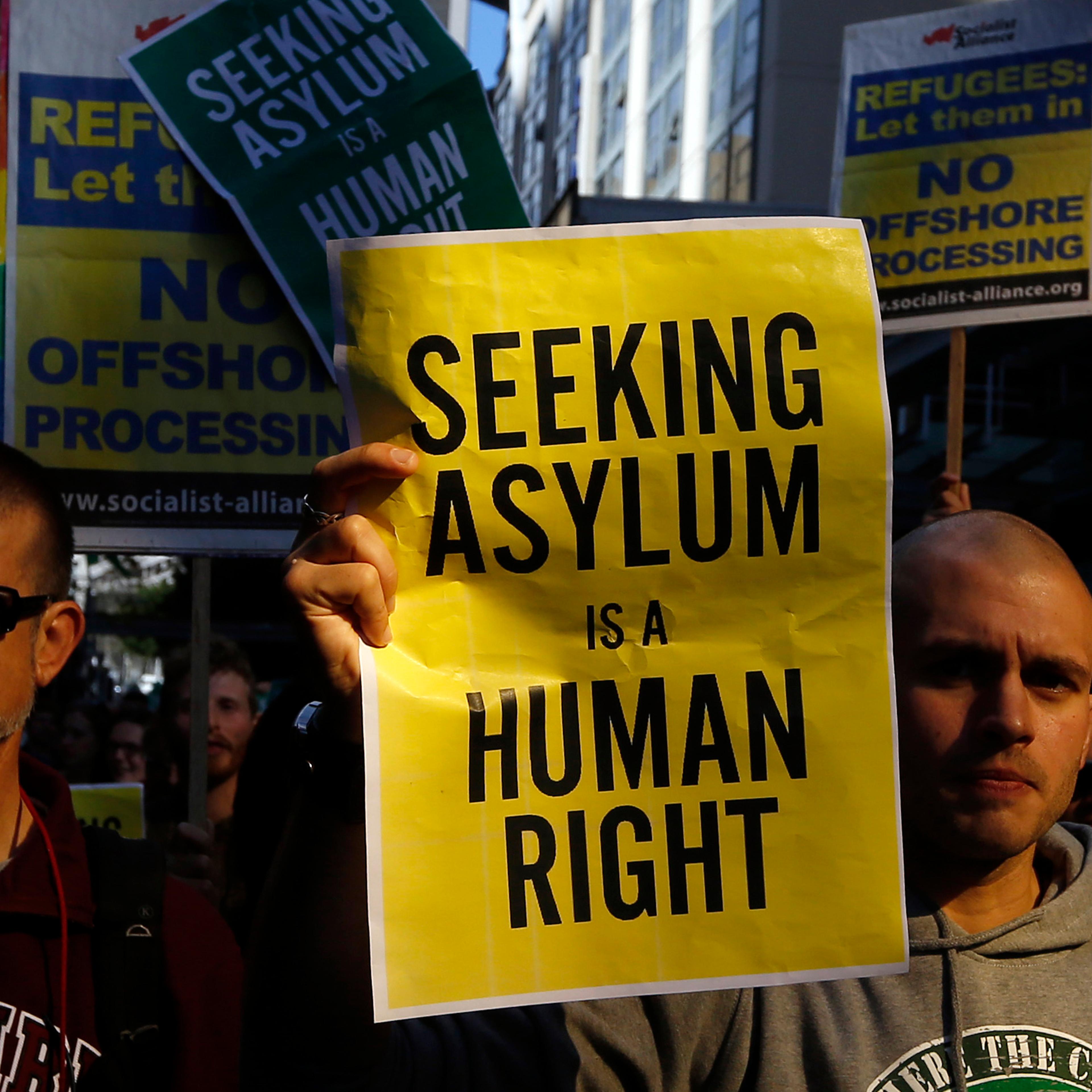 Man holds a poster during a rally in support of asylum seekers in central Sydney