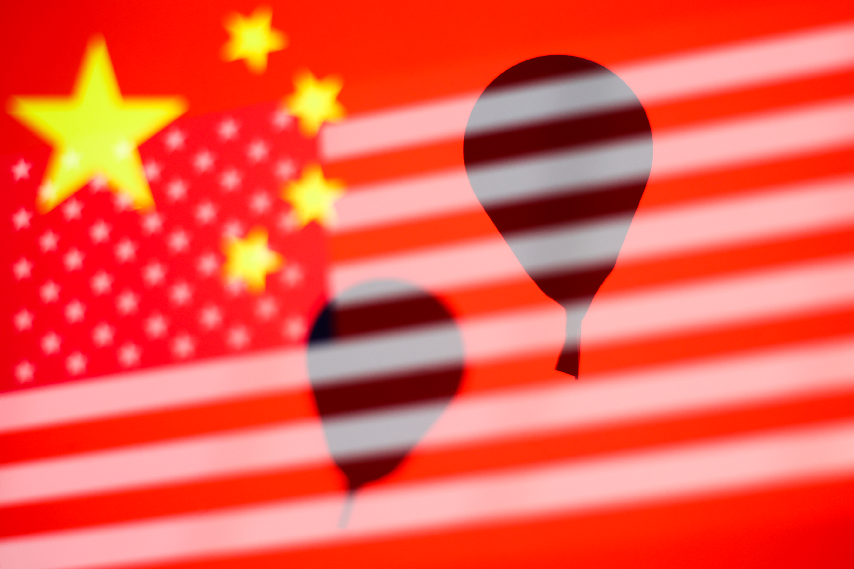 Balloon silhouettes are seen with Chinese and Americans flags in this multiple exposure illustration photo taken in Krakow, Poland, on Feb. 14, 2023.
