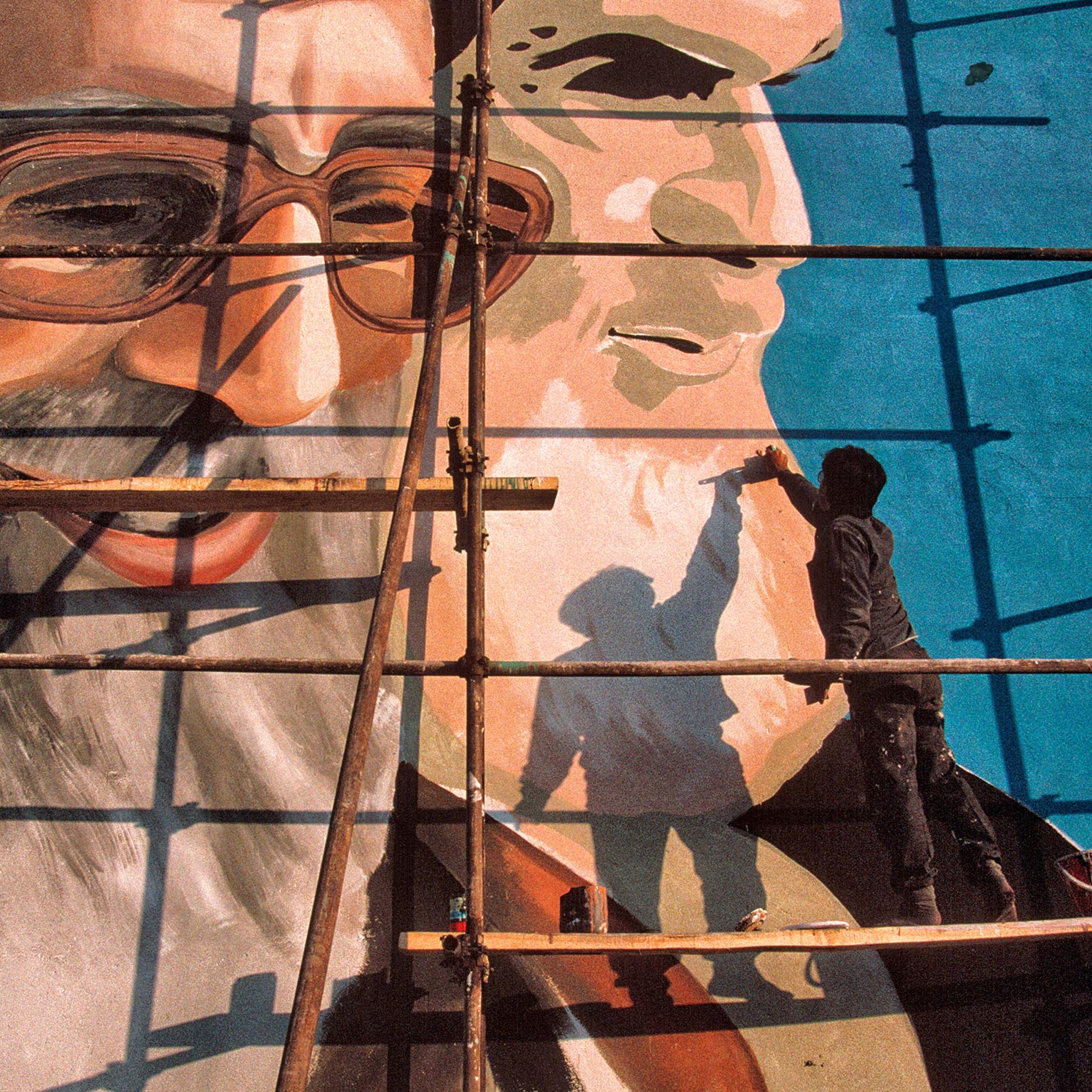 A painter works on a Tehran mural of Khamenei, left, and Iran’s first Supreme Leader, Ruhollah Khomeini