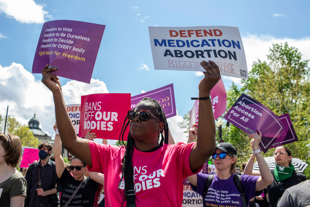 Activists holding abortion rights signs shout slogans during